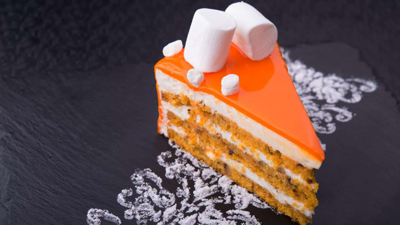 1366x768 Desserts 桌布 壁紙 — 一塊充滿活力的橙色糖霜層疊胡蘿蔔蛋糕片，上面放有迷你棉花糖，放在帶有糖粉漩渦的深色石板之上。