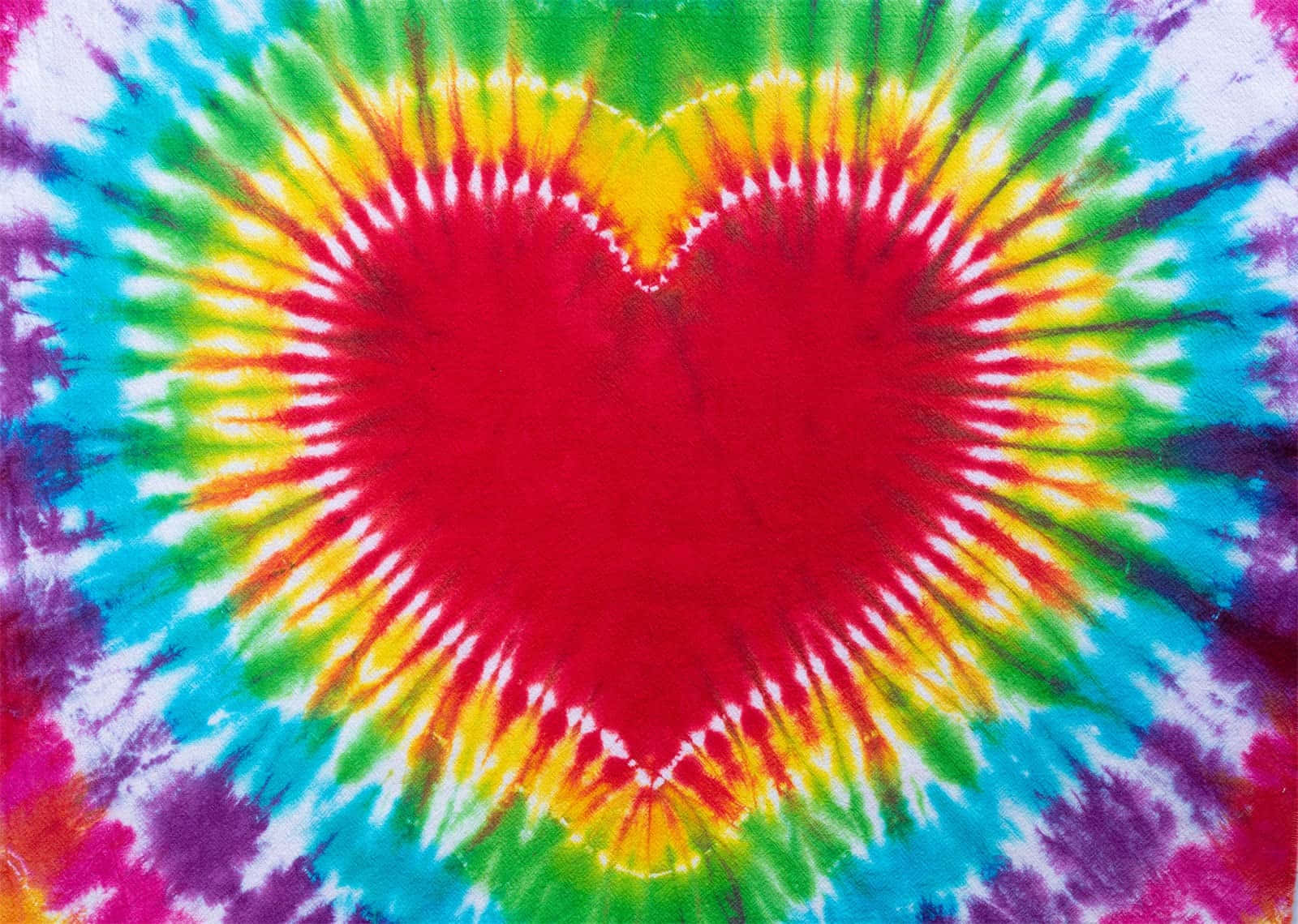 Rainbow Heart 桌布 壁紙 — 一塊充滿活力的紮染布料，中央有一個大膽的紅色心形，向外輻射出彩虹般的色彩，形成迷幻的爆發效果。