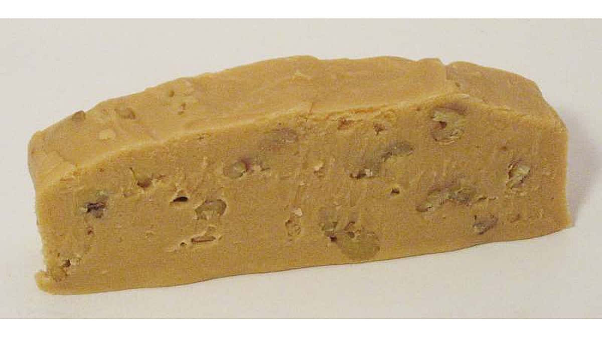 Penuche Fudge 桌布 壁紙 — 一塊光滑的金棕色軟糖條，上面綴有切碎的堅果，放在純白色的表面上。