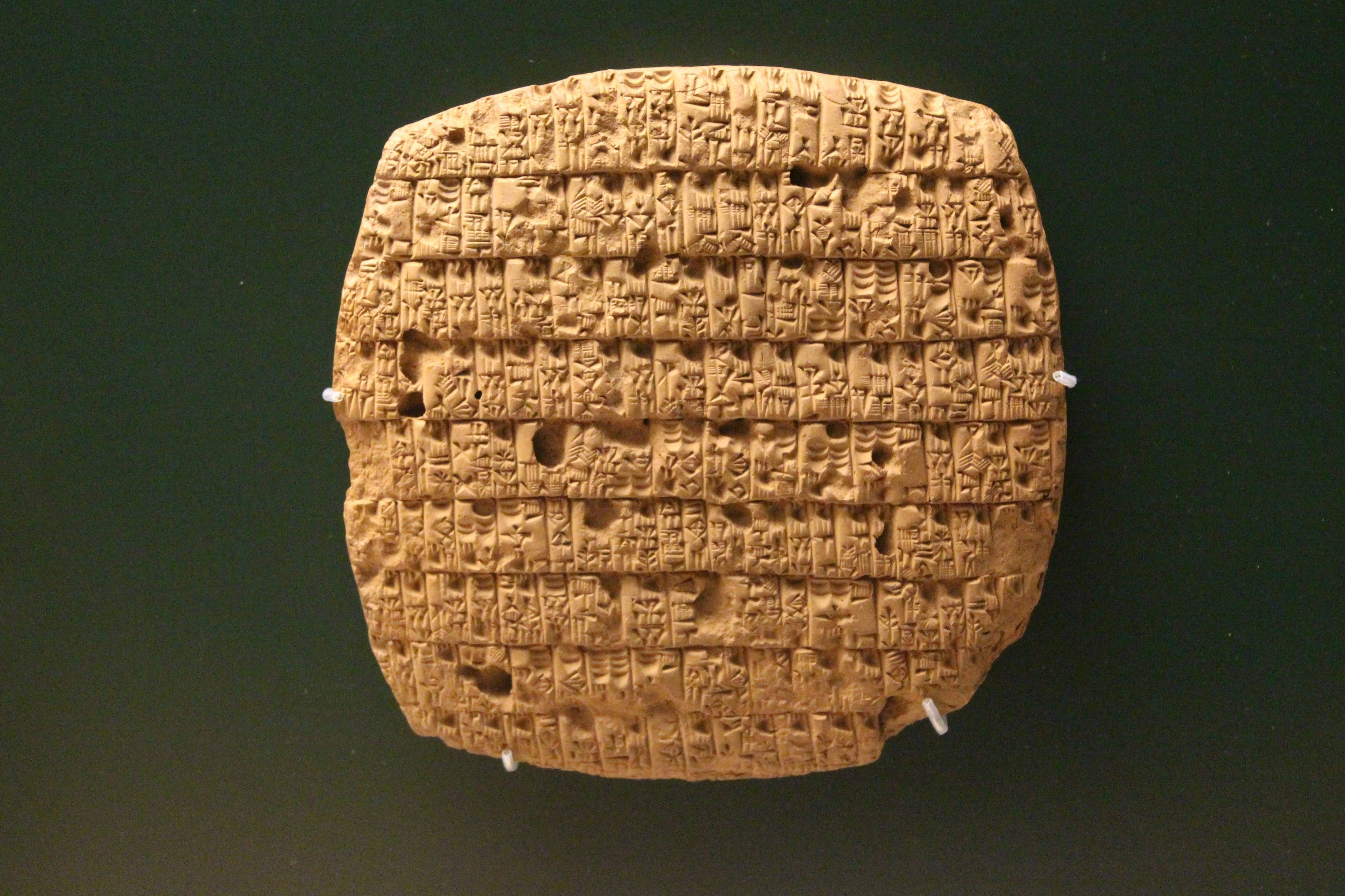 Iraq 桌布 壁紙 — 一塊古老的泥板，上面有複雜的楔形文字，展示在深綠色背景上。
