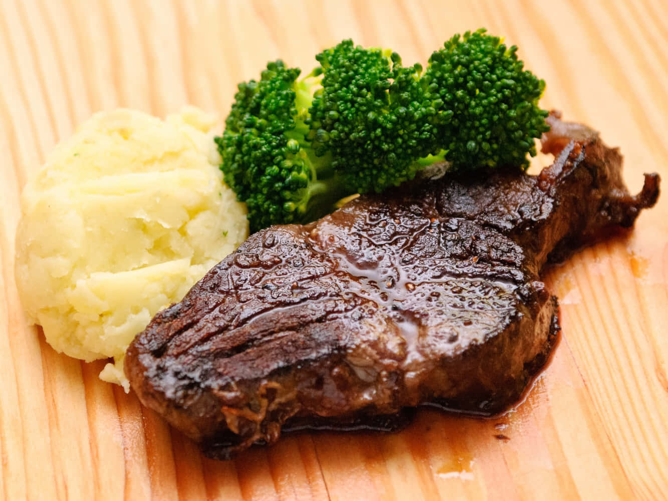 meat 桌布 壁紙 — 一塊多汁的煎牛排搭配馬鈴薯泥和鮮綠色的花椰菜，放在溫暖的木板上。