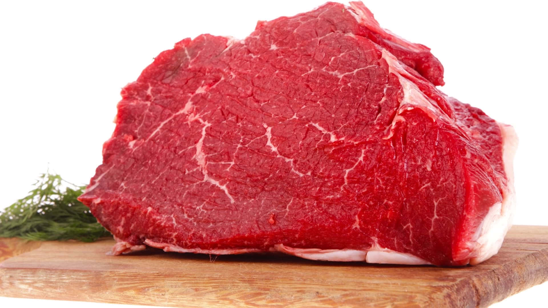 meat 桌布 壁紙 — 一塊多汁的生牛肉排，帶有雪花紋理，放在木砧板上，旁邊有新鮮蒔蘿，背景為白色。