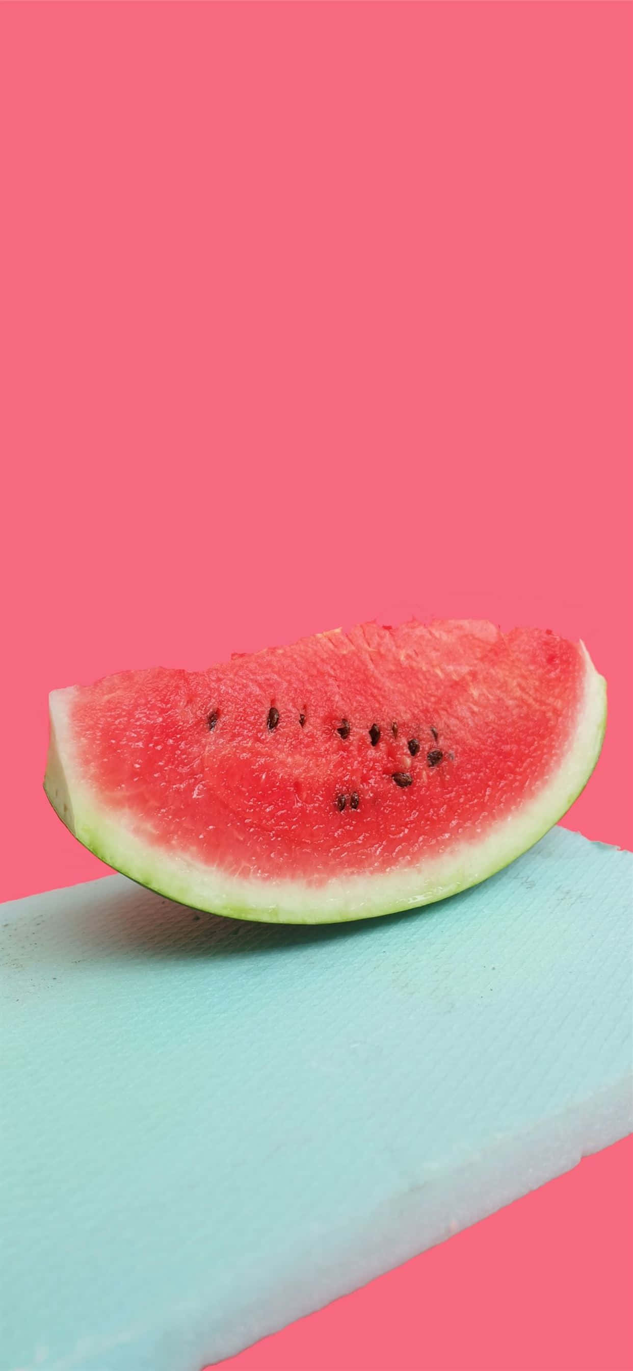 Watermelon iPhone 桌布 壁紙 — 一塊多汁的西瓜切片帶有黑色種子，放在淺藍色砧板上，背景是充滿活力的粉紅色。