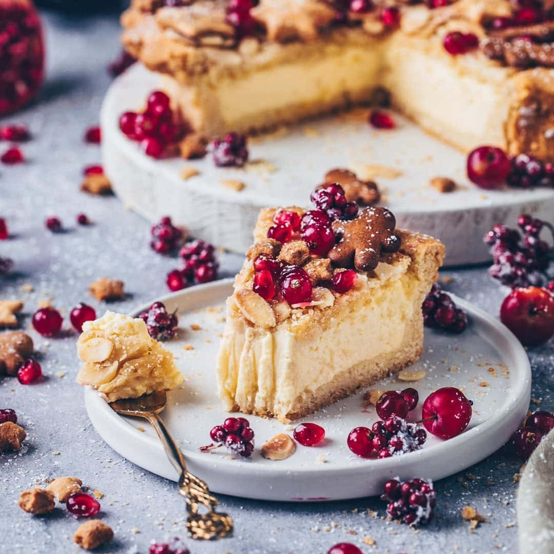 Winter Desserts 桌布 壁紙 — 一塊奶油起司蛋糕，上面鋪滿蔓越莓和堅果，放在盤子上，旁邊有一把金色叉子。