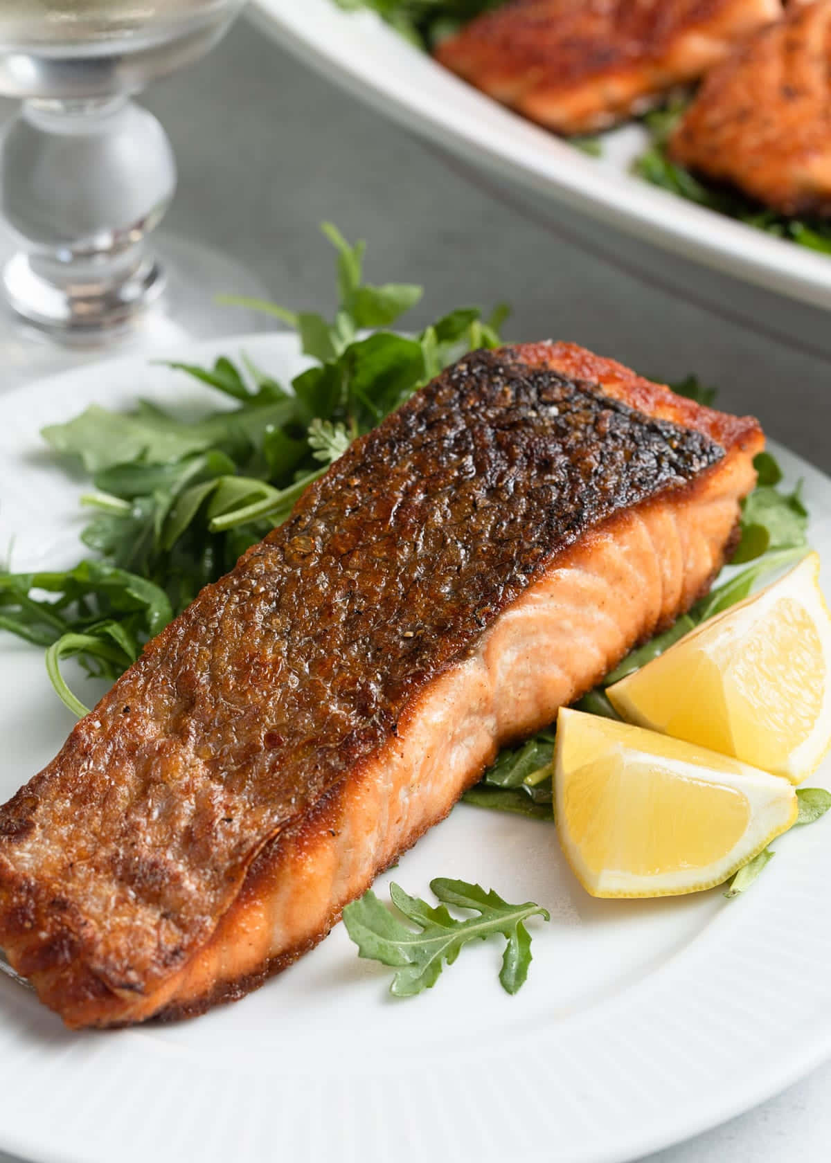Salmon 桌布 壁紙 — 一塊完美煎封的鮭魚排放在芝麻葉上，搭配檸檬角，置於白色盤中。