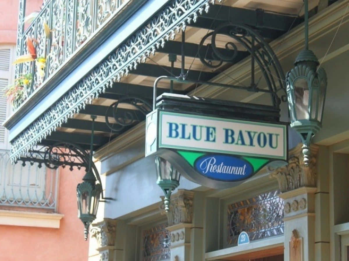 Blue Bayou 桌布 壁紙 — 一塊寫有「BLUE BAYOU」的復古餐廳招牌懸掛在裝飾性的鍛鐵陽台下，並配有吊燈。