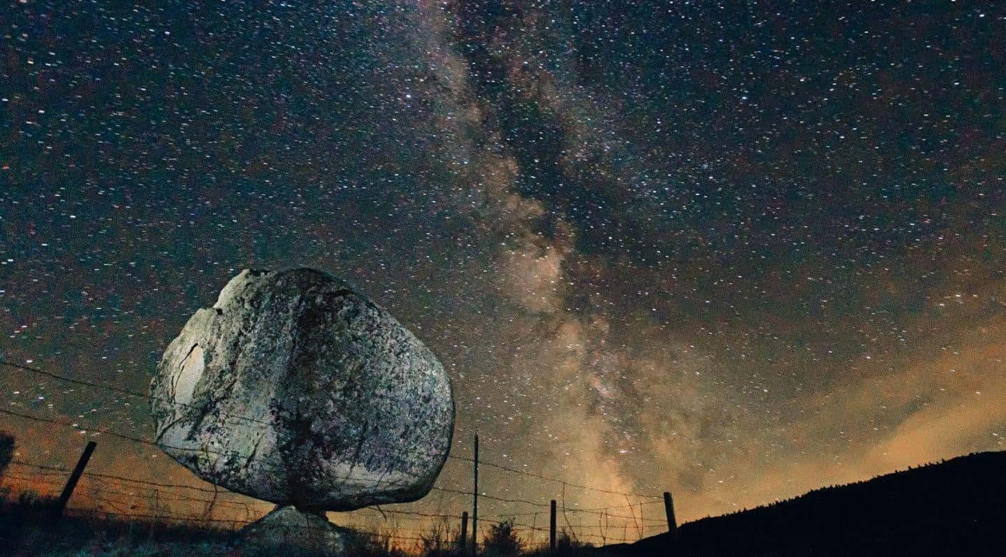銀河 桌布 壁紙 — 一塊巨大的岩石坐落於繁星點點的夜空下，銀河在頭頂閃耀。