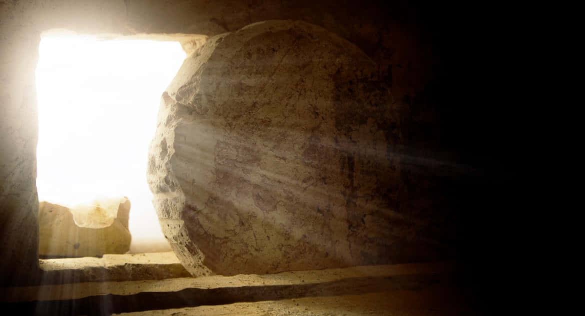 Resurrection 桌布 壁紙 — 一塊巨大的石板擋住了墓穴入口，燦爛的陽光從開口處湧入，在古老的石室內部投射出戲劇性的光束。