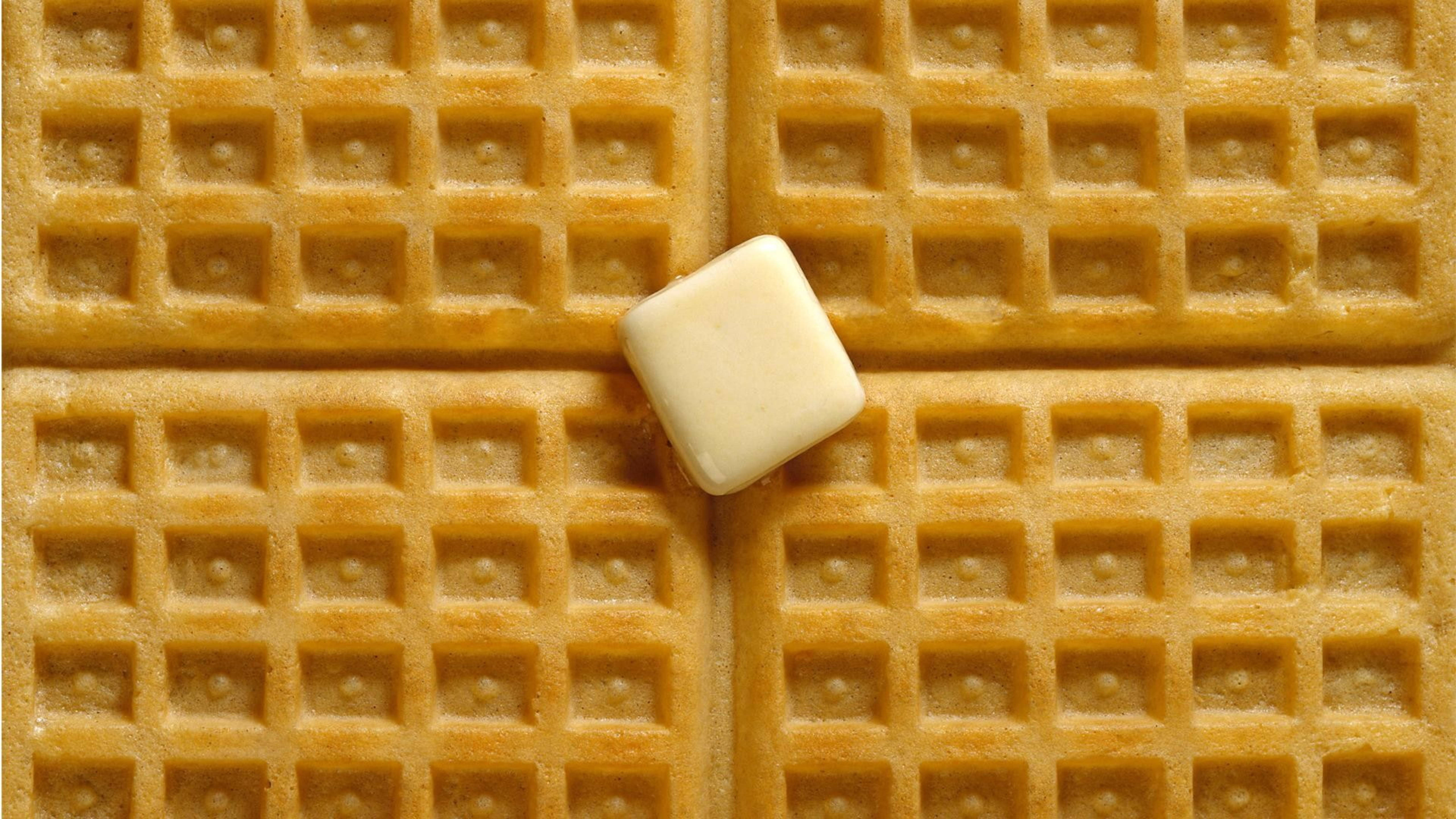Waffle 桌布 壁紙 — 一塊方形奶油放在金黃色的鬆餅格上，特寫俯拍鏡頭。