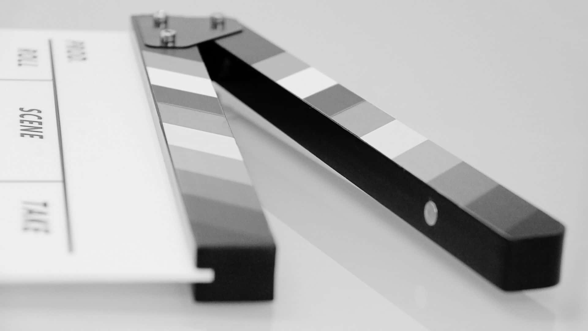Black And White Movie 桌布 壁紙 — 一塊時尚的黑白電影拍板斜放在簡約的白色表面上，帶有柔和陰影。