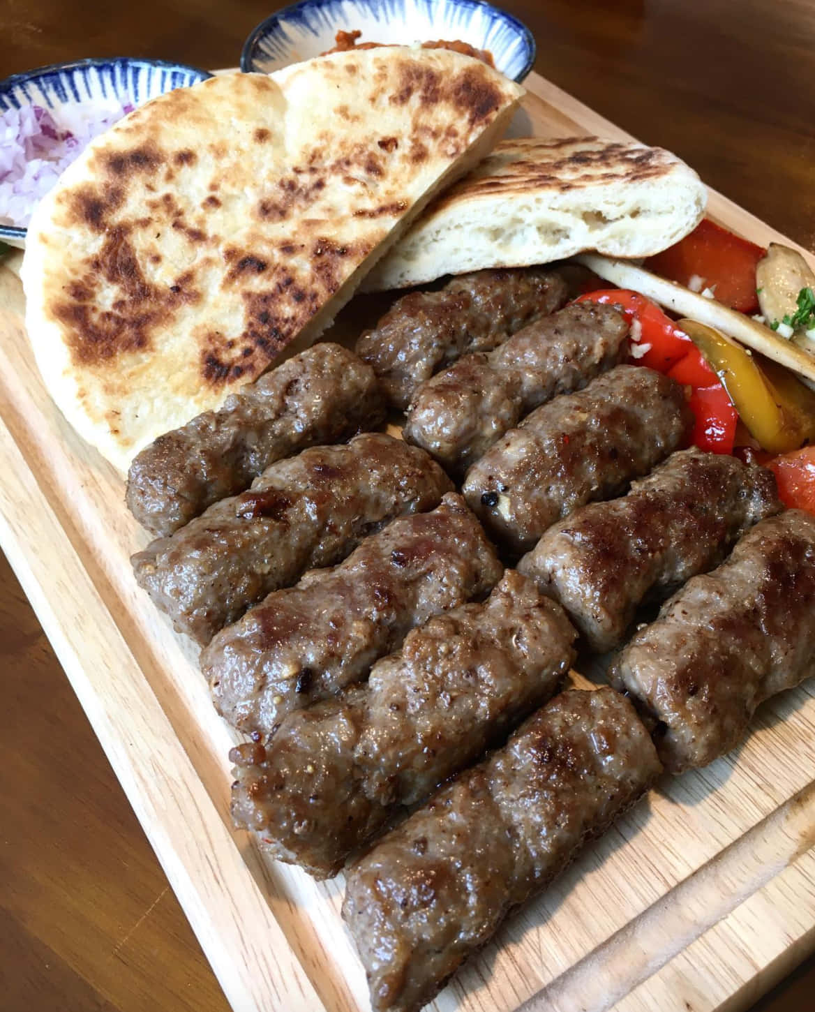 meat 桌布 壁紙 — 一塊木板上放著帶有燒焦痕跡的烤香腸，還有扁麵包和色彩繽紛的甜椒。