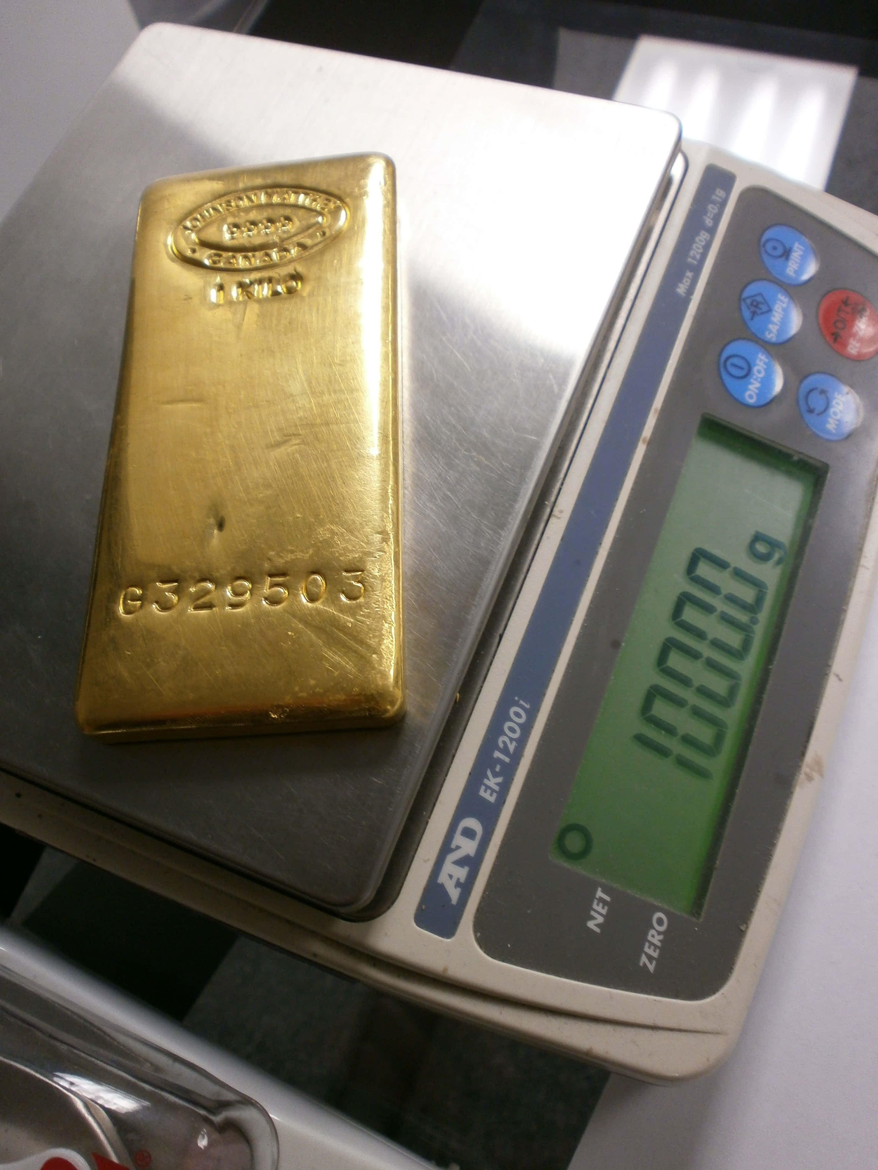 Gold Bars 桌布 壁紙 — 一塊標有「1000g」的實心金條放在顯示其準確重量的數位精密秤上。