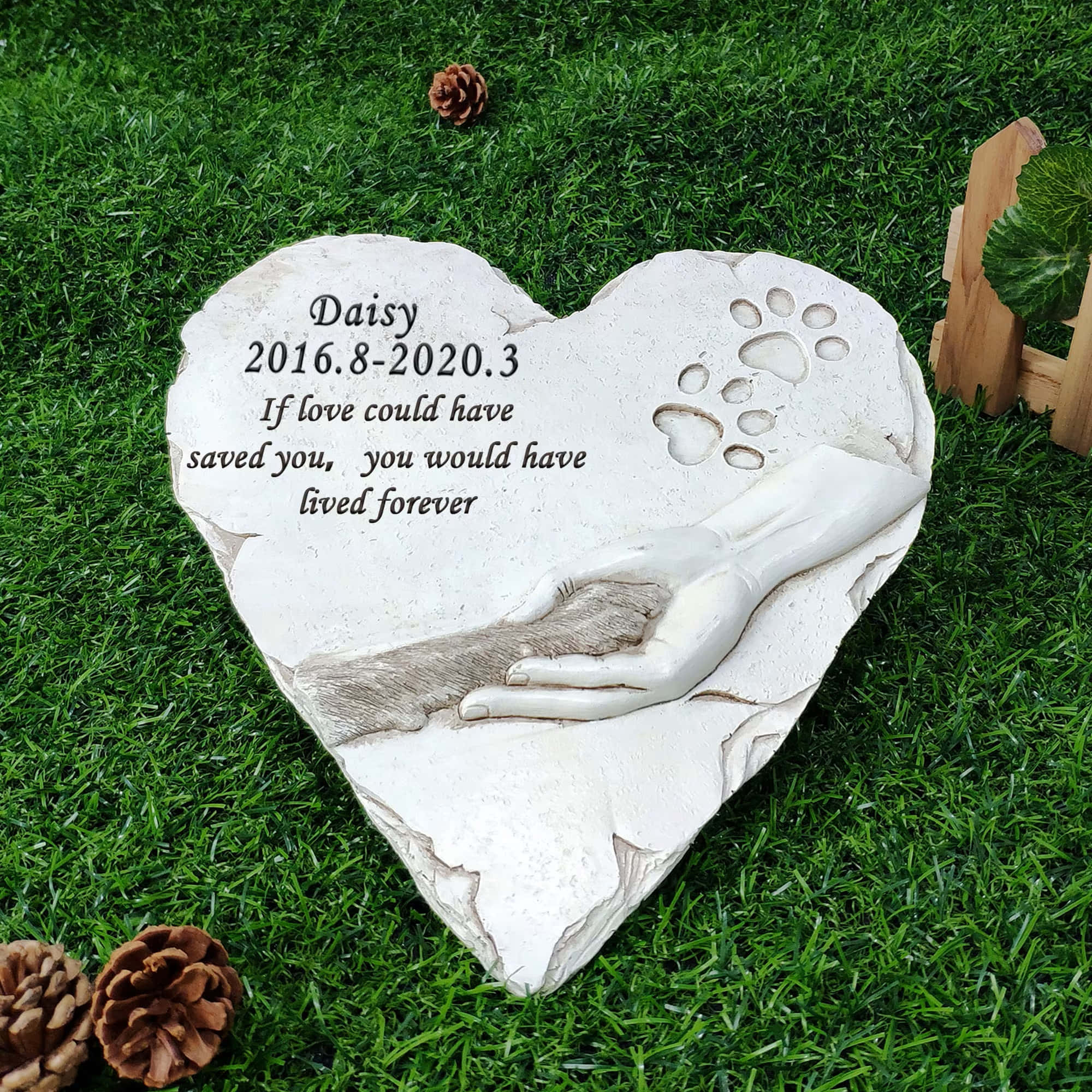Memorial 桌布 壁紙 — 一塊白色心形紀念石，刻有爪印和握著毛髮的手，放置在鮮綠色的草地上，附近有松果。