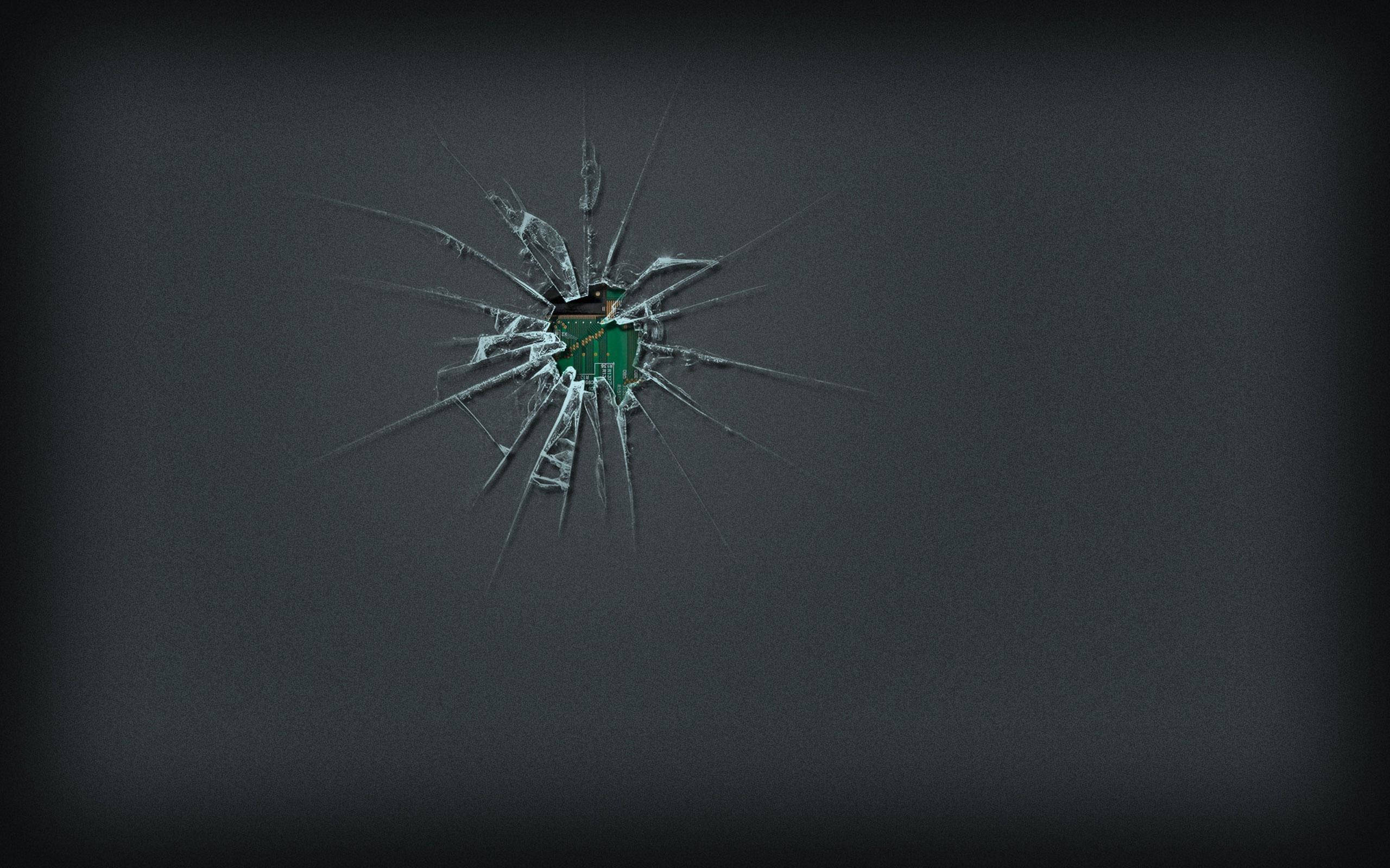 Screen 桌布 壁紙 — 一塊破碎的玻璃板，透過裂縫可見一個綠色物體，背景為深灰色。