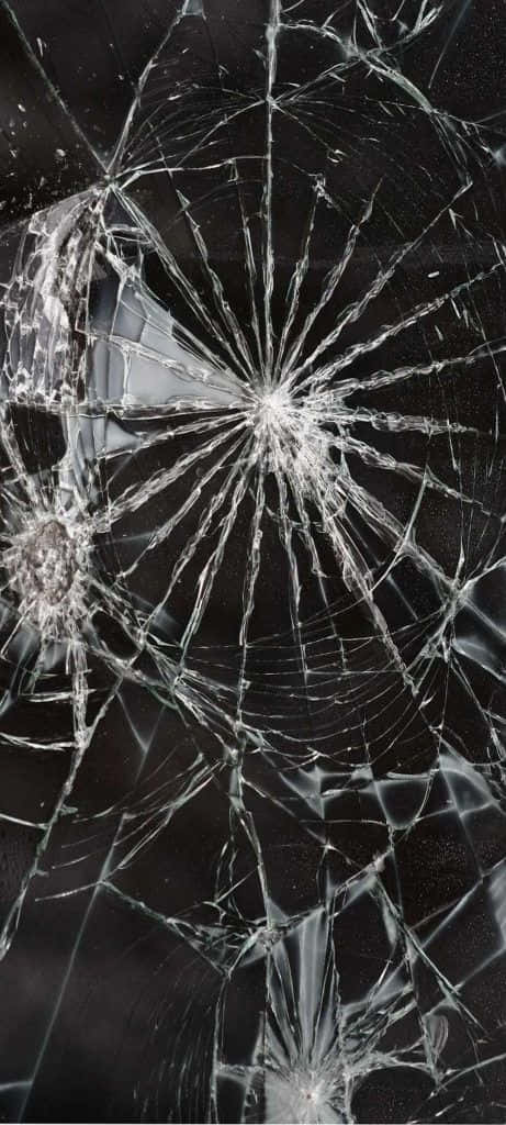 Broken 桌布 壁紙 — 一塊破碎的玻璃表面，從中央撞擊點散發出複雜的裂紋，背景為深色。