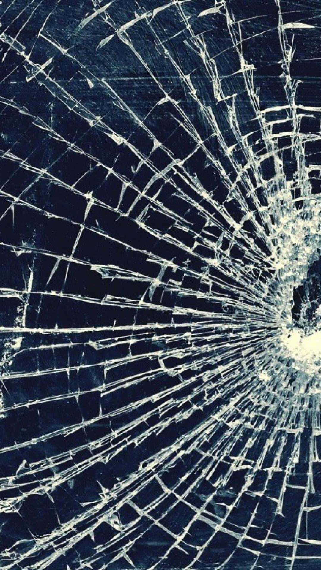 Fracture Glass 桌布 壁紙 — 一塊破碎的玻璃表面，白色裂紋從中央撞擊點向四周擴散，背景為深藍色。