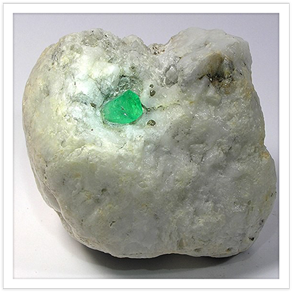 Gemstone 桌布 壁紙 — 一塊粗糙的白色岩石，中心嵌有一顆鮮豔的綠色祖母綠晶體。