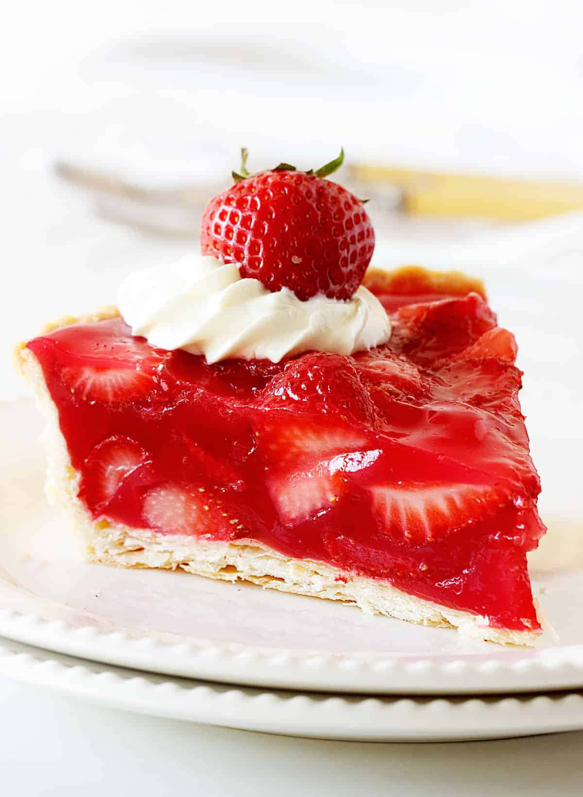 Strawberries 桌布 壁紙 — 一塊色彩鮮豔的草莓派，上面有鮮奶油和一整顆草莓，放在白色盤子上。