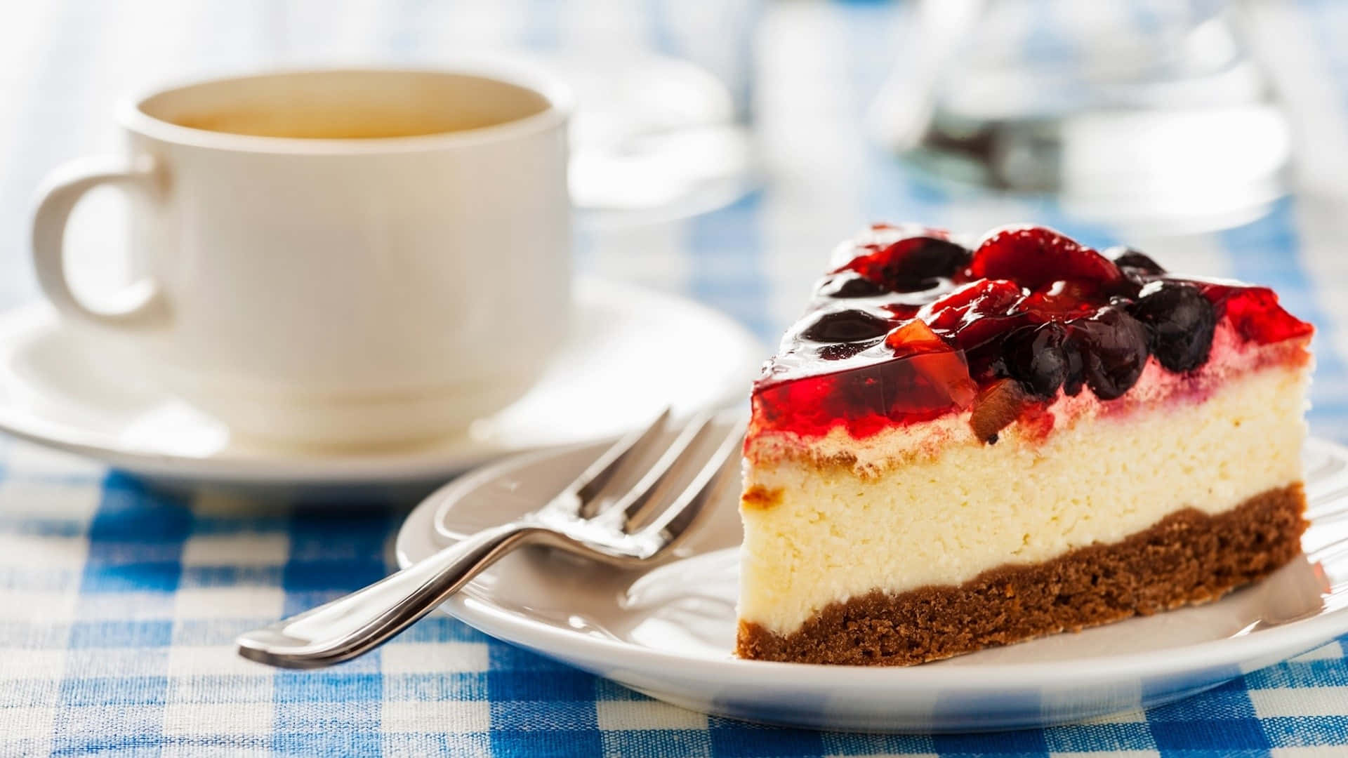 Desserts 桌布 壁紙 — 一塊莓果頂層起司蛋糕放在藍色格子桌布上，旁邊有一杯茶。