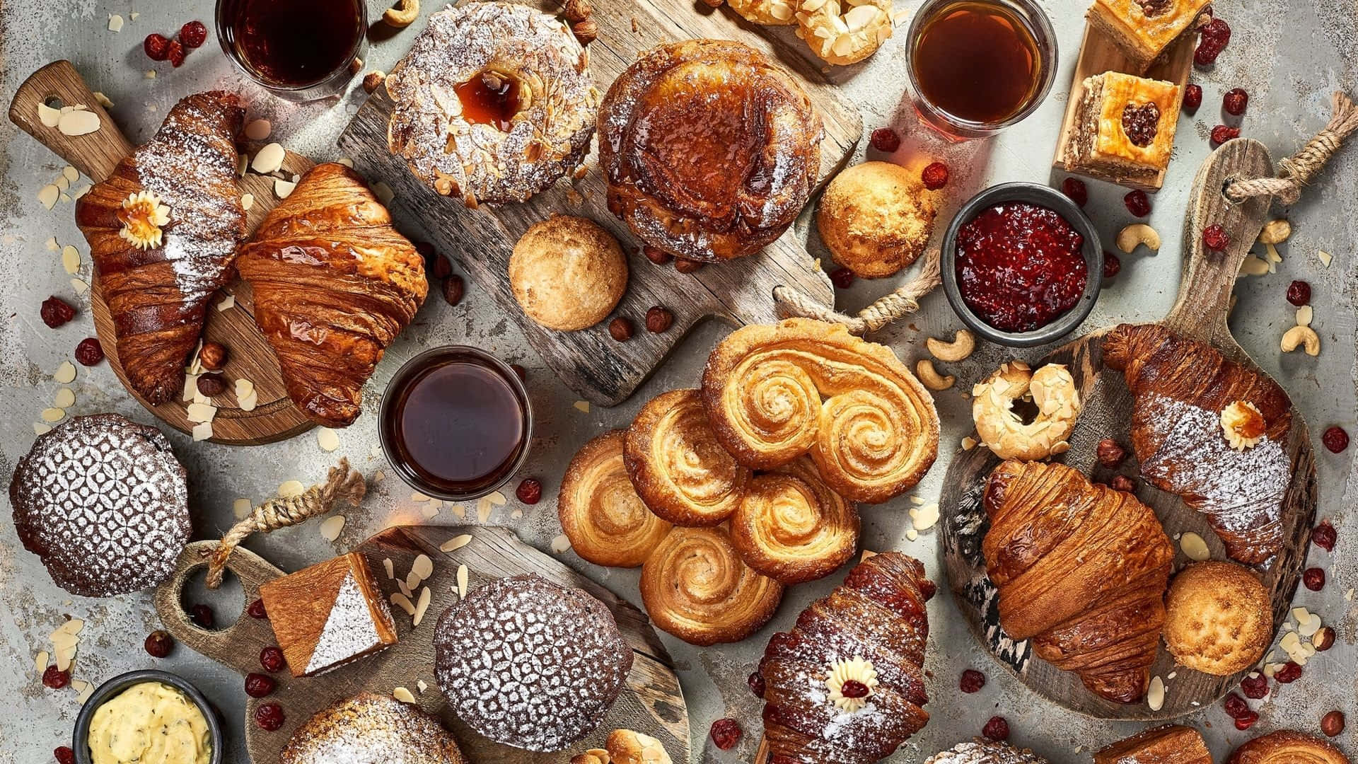 Pastry 桌布 壁紙 — 一塊質樸的木板上擺放著各種金黃色的糕點、可頌、丹麥酥和果醬，營造出舒適的早餐氛圍。