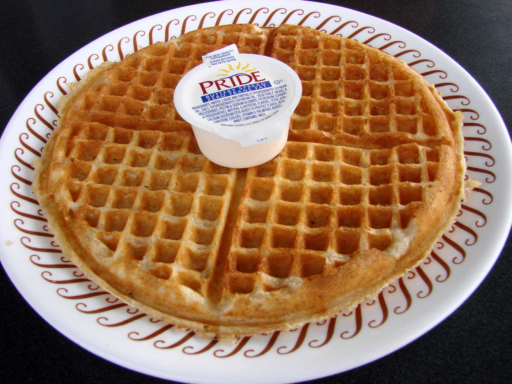 Waffle 桌布 壁紙 — 一塊金黃色的鬆餅放在帶有棕色渦紋的白色盤子上，上面放著一小盒奶油。