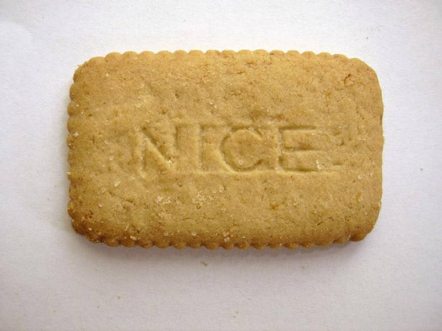 好看 桌布 壁紙 — 一塊金黃色長方形餅乾，上面壓印有「NICE」字樣，放在純白色表面上。