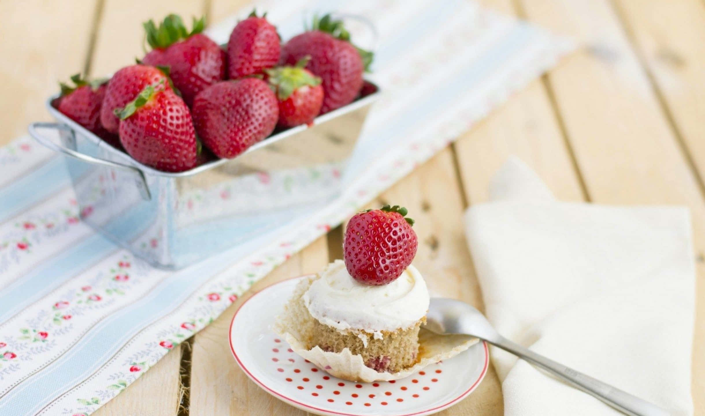 2440x1440 Desserts 桌布 壁紙 — 一塊鋪上新鮮莓果的草莓蛋糕片放在木桌上，旁邊是一個裝滿成熟草莓的金屬碗。