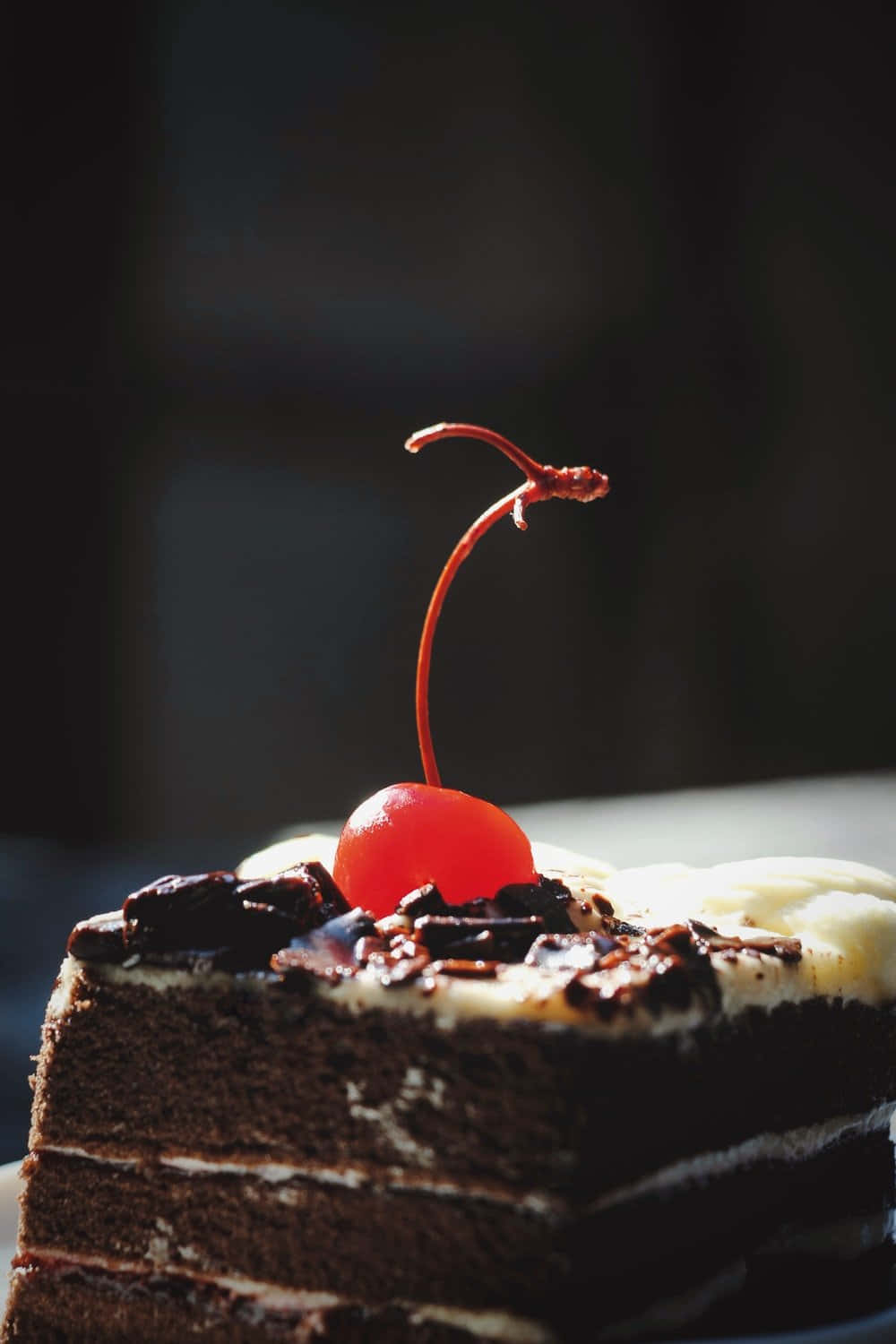 Black Forest Cake 桌布 壁紙 — 一塊頹廢的巧克力蛋糕，上面有鮮奶油和一顆鮮紅的櫻桃，放在深色背景上。