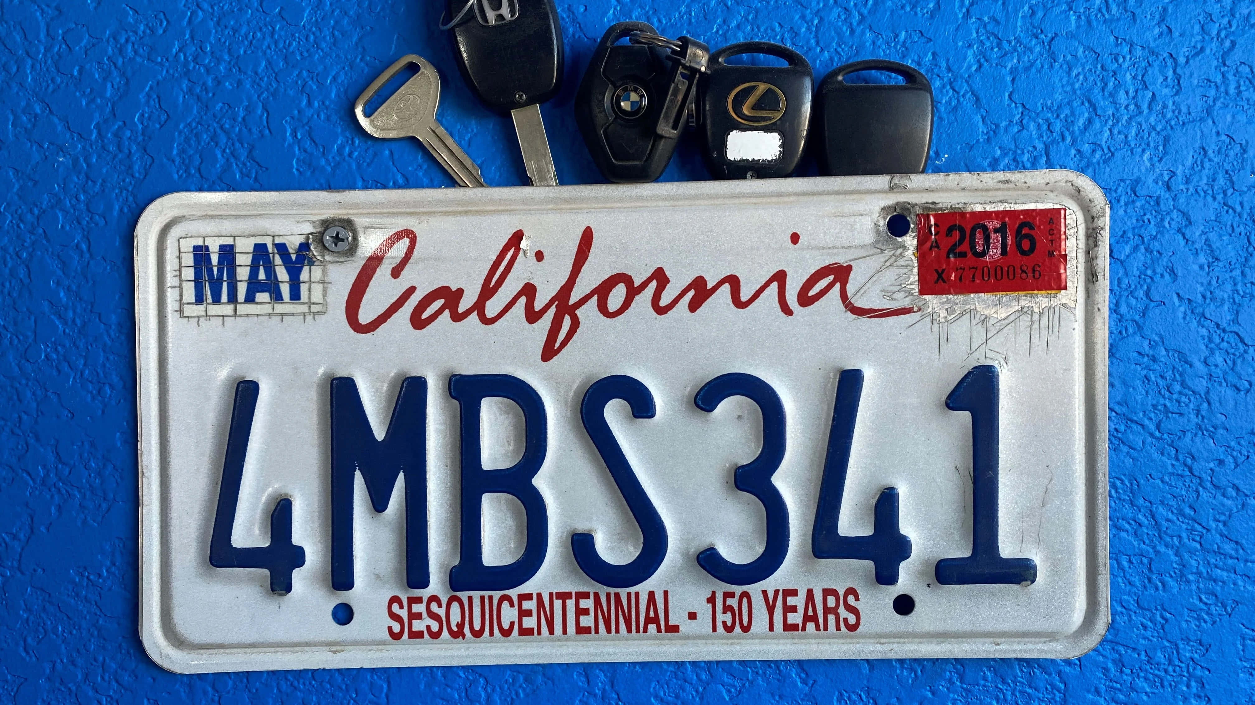 License Plate 桌布 壁紙 — 一塊風化的加州車牌連同鑰匙放在有紋理的藍色牆上。