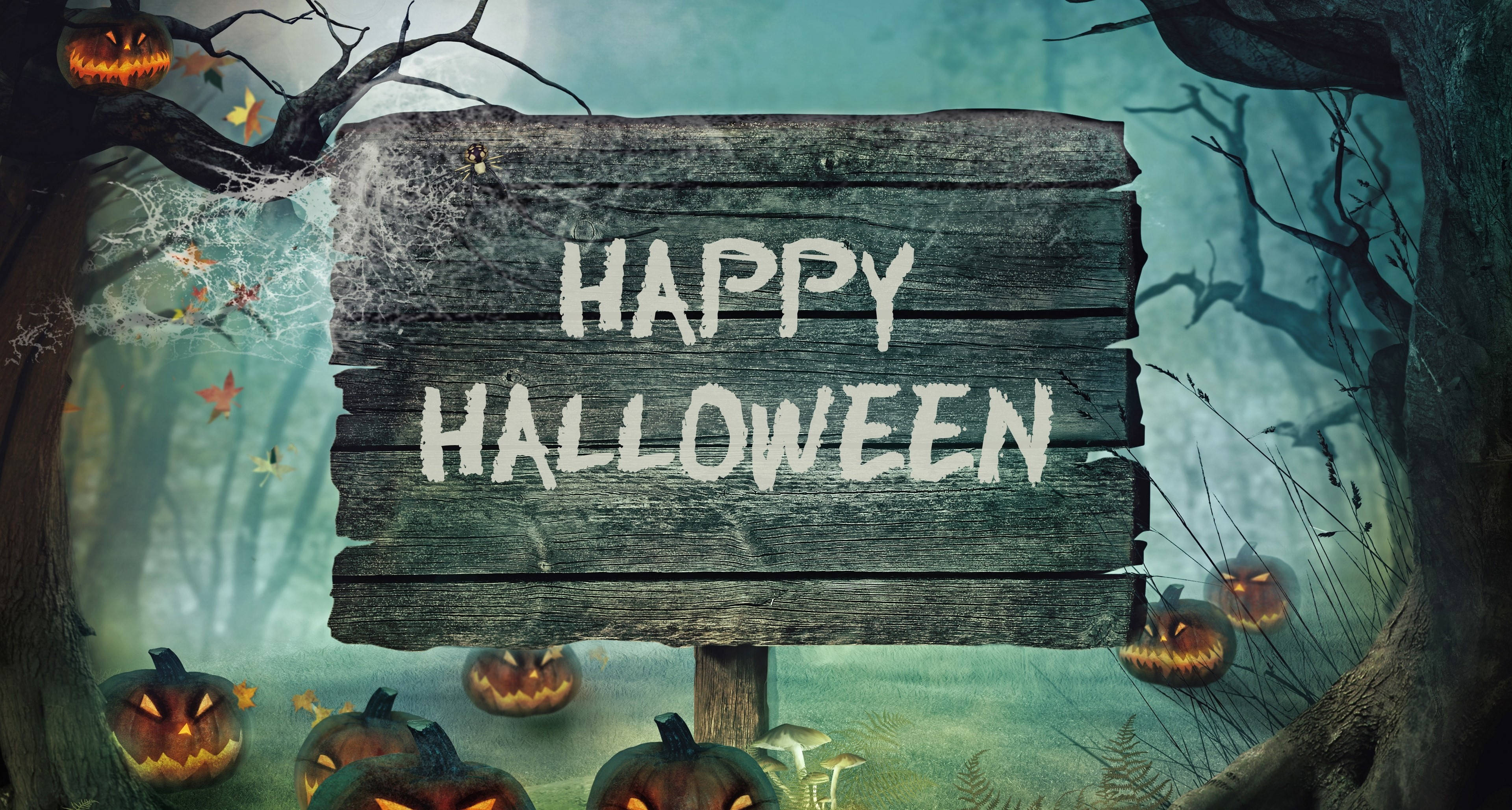 Happy Halloween 桌布 壁紙 — 一塊風化的木牌上寫著「HAPPY HALLOWEEN」，矗立在迷霧森林中，周圍環繞著發光的傑克南瓜燈和光禿扭曲的樹木。