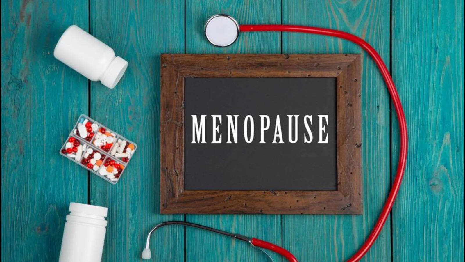 Menopause 桌布 壁紙 — 一塊黑板，上面寫著「MENOPAUSE」，周圍環繞著藥丸和聽診器，放在青綠色木頭上。