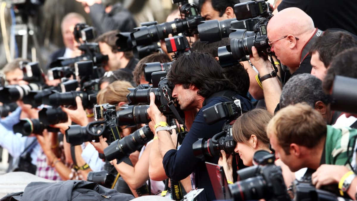 Paparazzi 桌布 壁紙 — 一大群攝影師手持大型專業相機，專注於畫面外的拍攝對象。