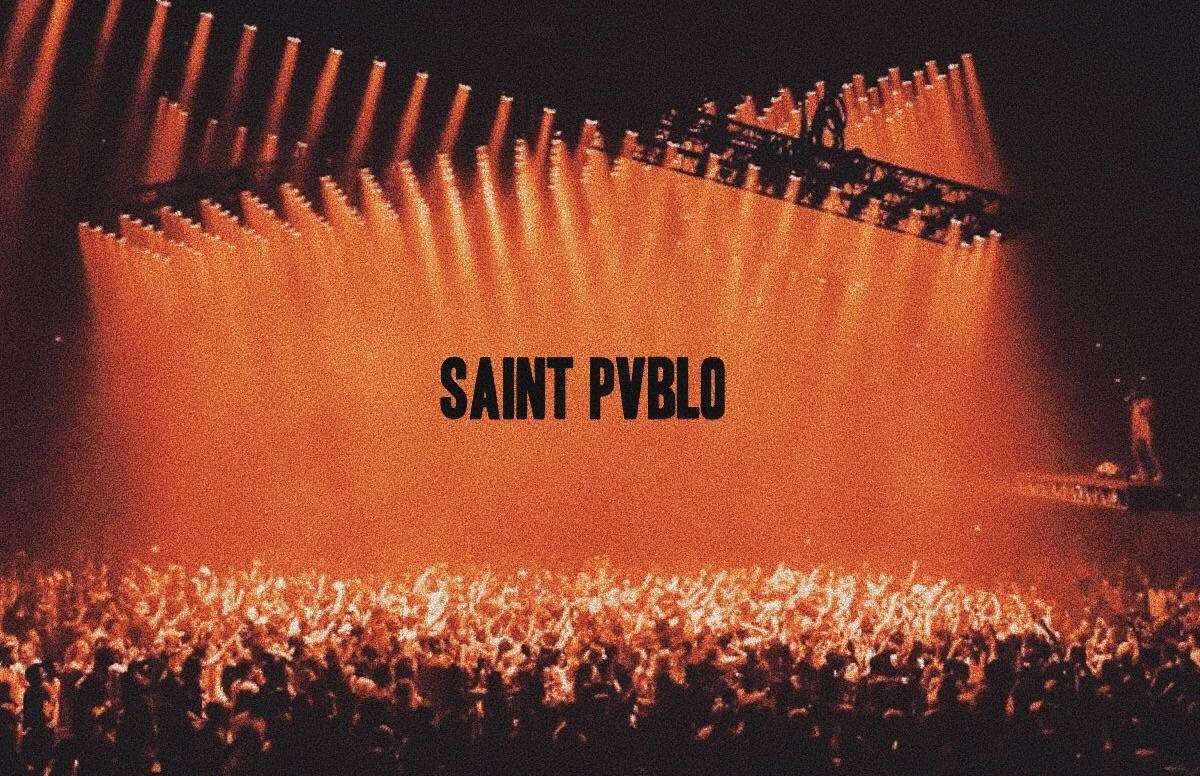 Kanye 桌布 壁紙 — 一大群演唱會觀眾沐浴在溫暖的橙色舞台燈光中，'SAINT PVBLO' 文字在充滿活力的觀眾上方閃耀。