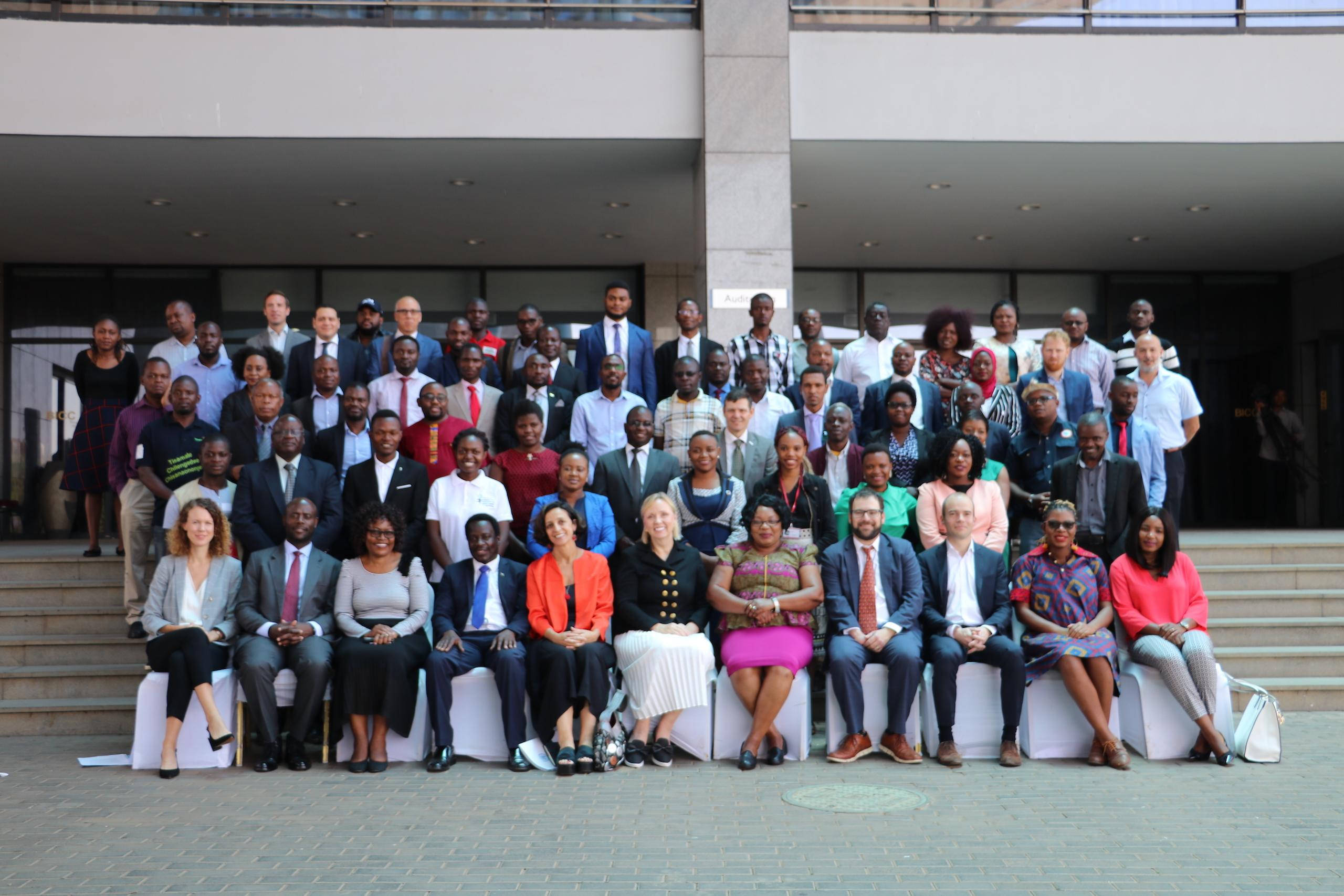 Malawi 桌布 壁紙 — 一大群穿著商務服裝的多元專業人士在現代建築外的階梯上正式擺姿勢。