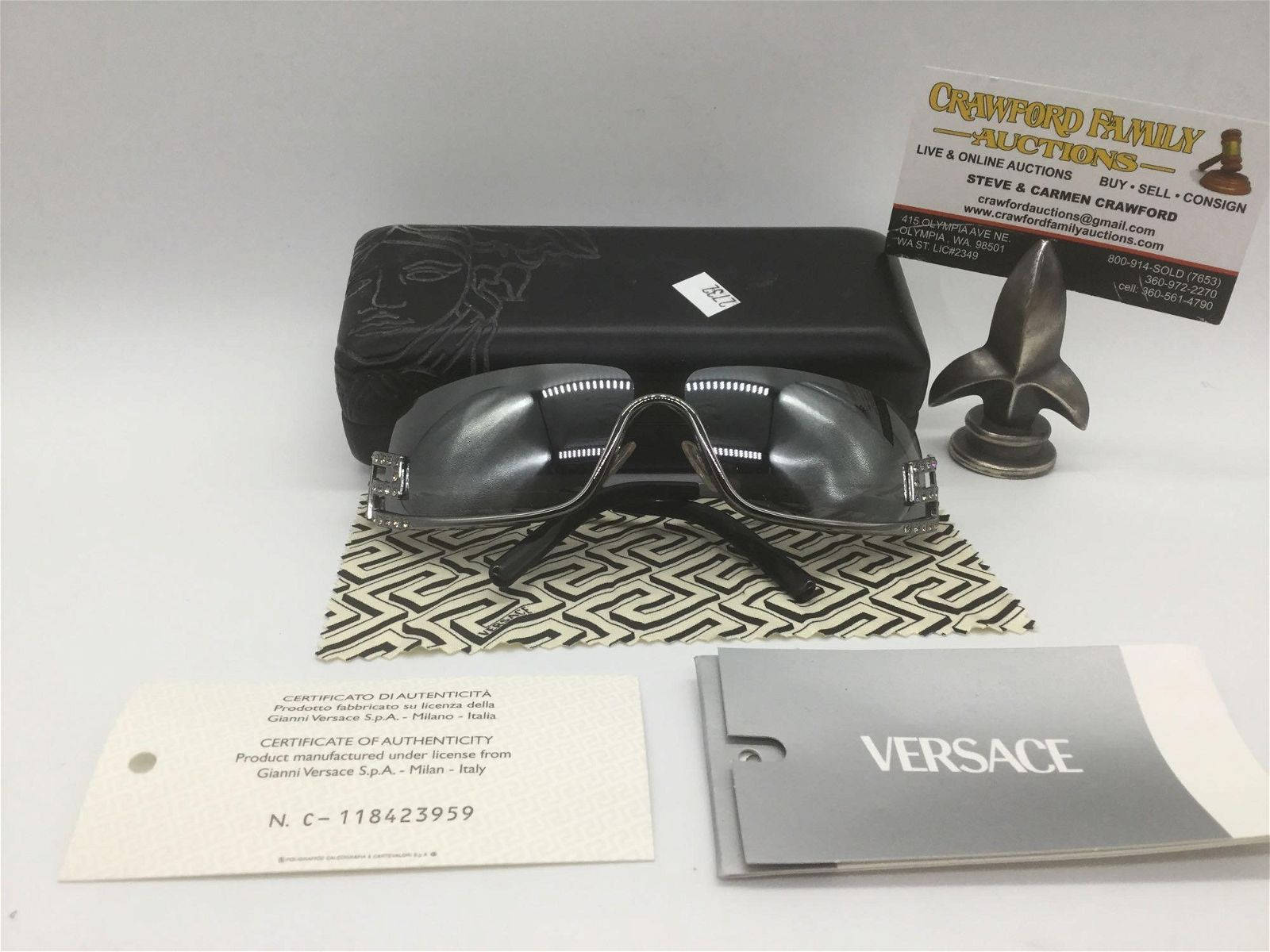 黑色 桌布 壁紙 — 一套時尚的黑色 Versace 太陽眼鏡，連同原裝眼鏡盒、證書及品牌包裝，展示在圖案布上。