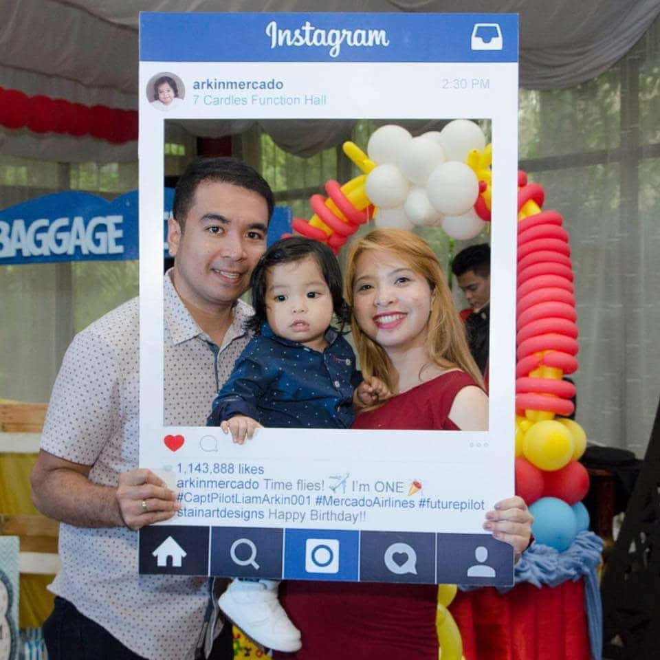 Photo Booth 桌布 壁紙 — 一家三口在生日慶祝活動中，在一個巨大的Instagram框架內微笑，周圍環繞著彩色氣球。