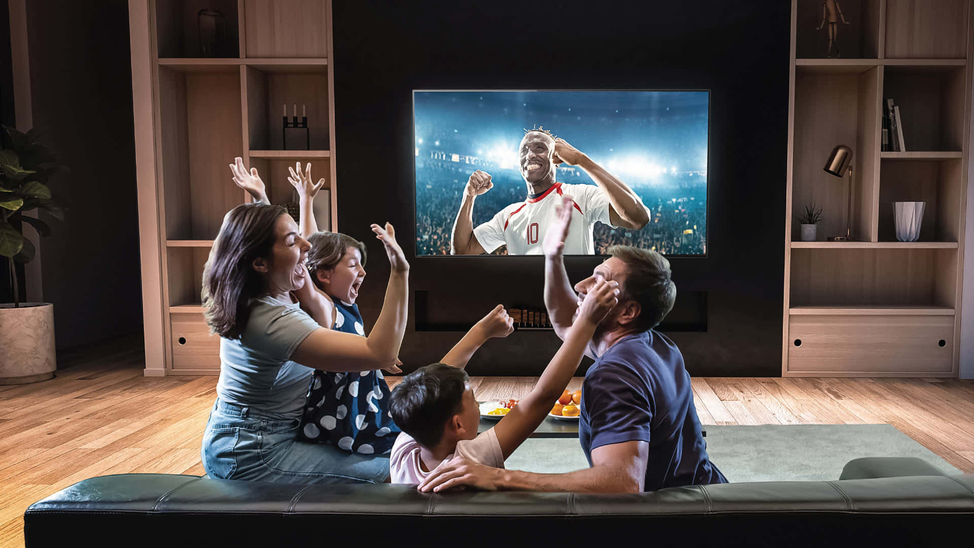 Home Entertainment 桌布 壁紙 — 一家人在沙發上瘋狂歡呼，因為足球員在他們舒適的客廳電視螢幕上慶祝。