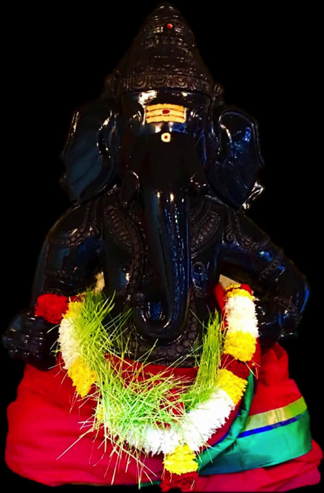 Hindu God 桌布 壁紙 — 一尊亮黑色象頭神雕像，飾以鮮豔的紅、黃、白色花環，置於純黑背景前。