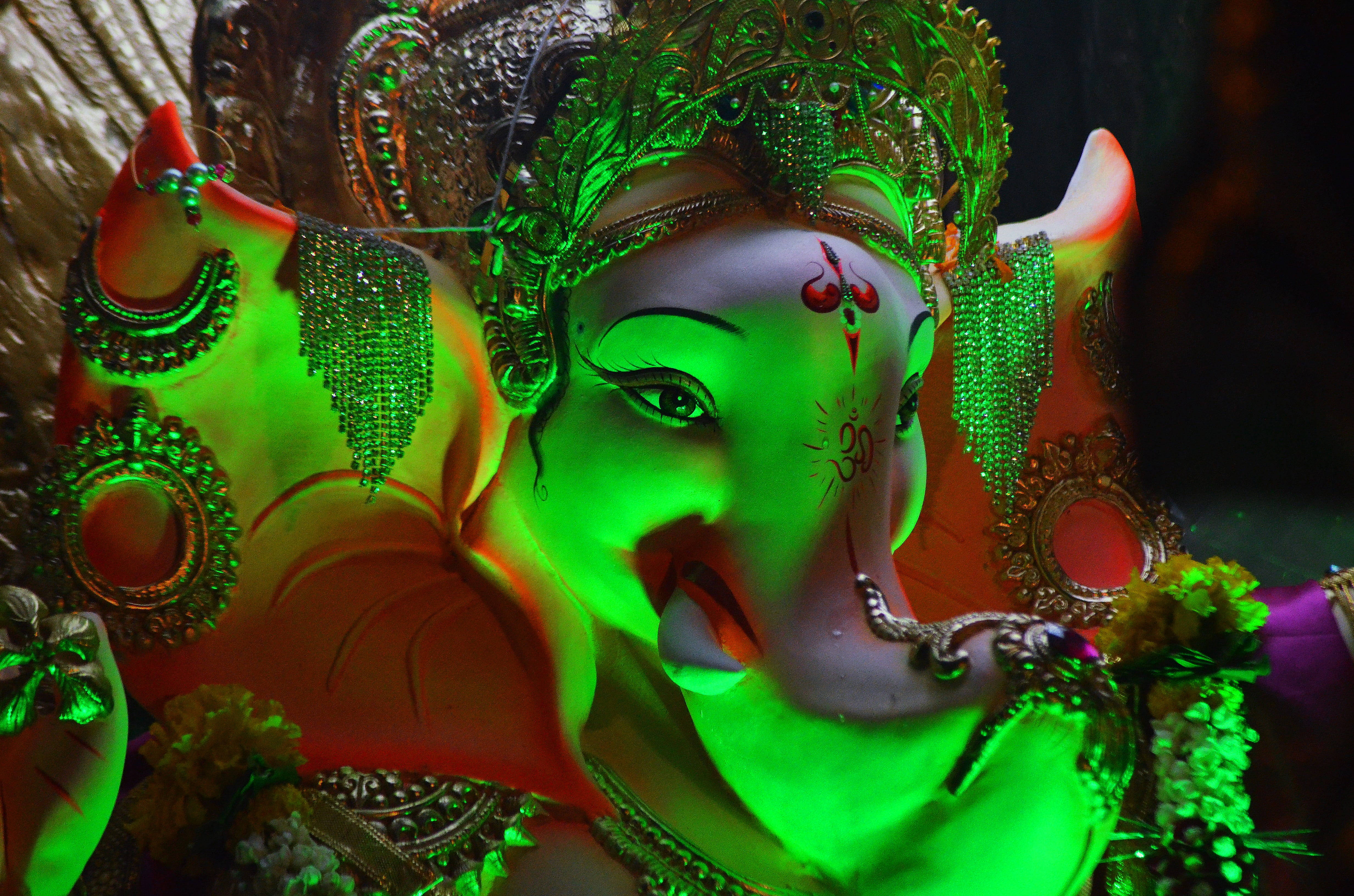 Hindu God 桌布 壁紙 — 一尊充滿活力的綠色發光象神像，飾有精緻珠寶和花環。
