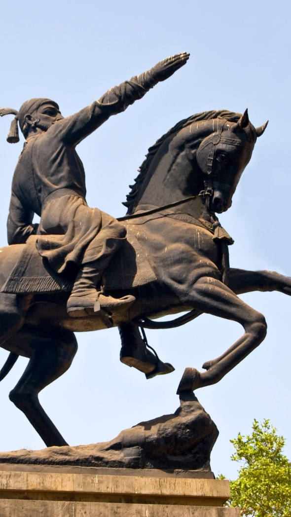 Chhatrapati Shivaji Maharaj 桌布 壁紙 — 一尊動態的青銅騎馬戰士雕像，戰士騎在後腿直立的馬上，背景是清澈的藍天。