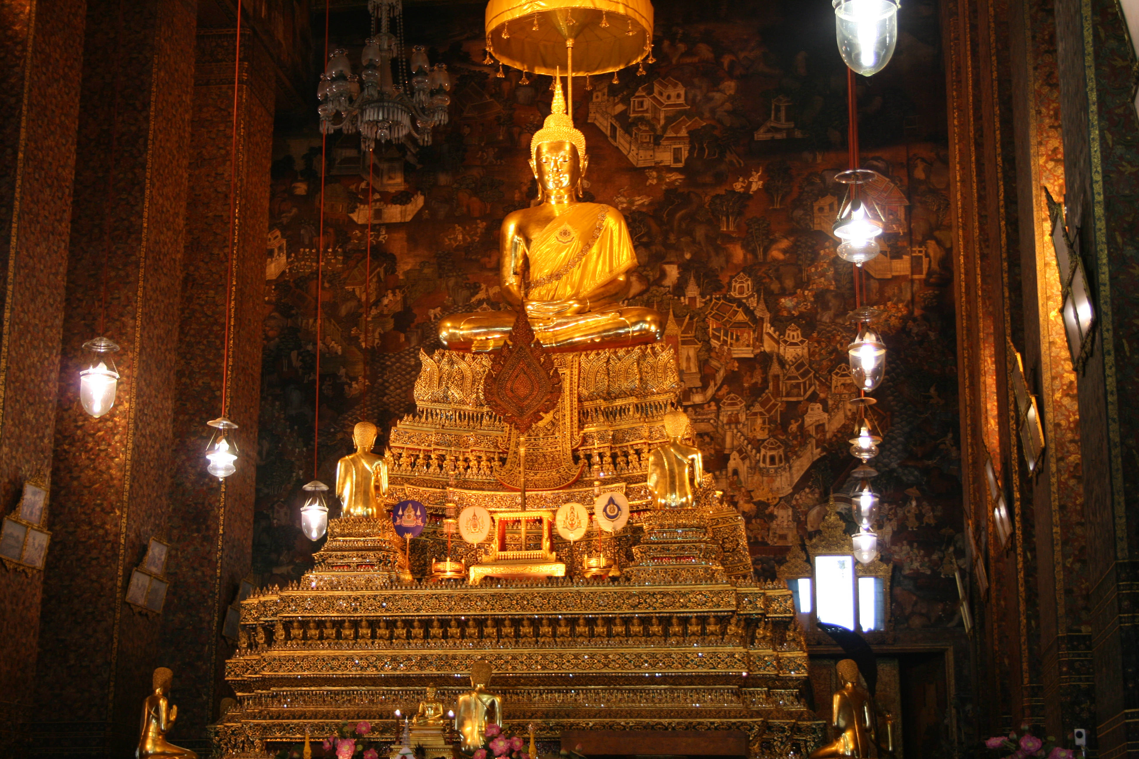 Bangkok 桌布 壁紙 — 一尊宏偉的金色佛像安詳地坐在華麗的分層基座上，位於裝飾華麗的寺廟內部。