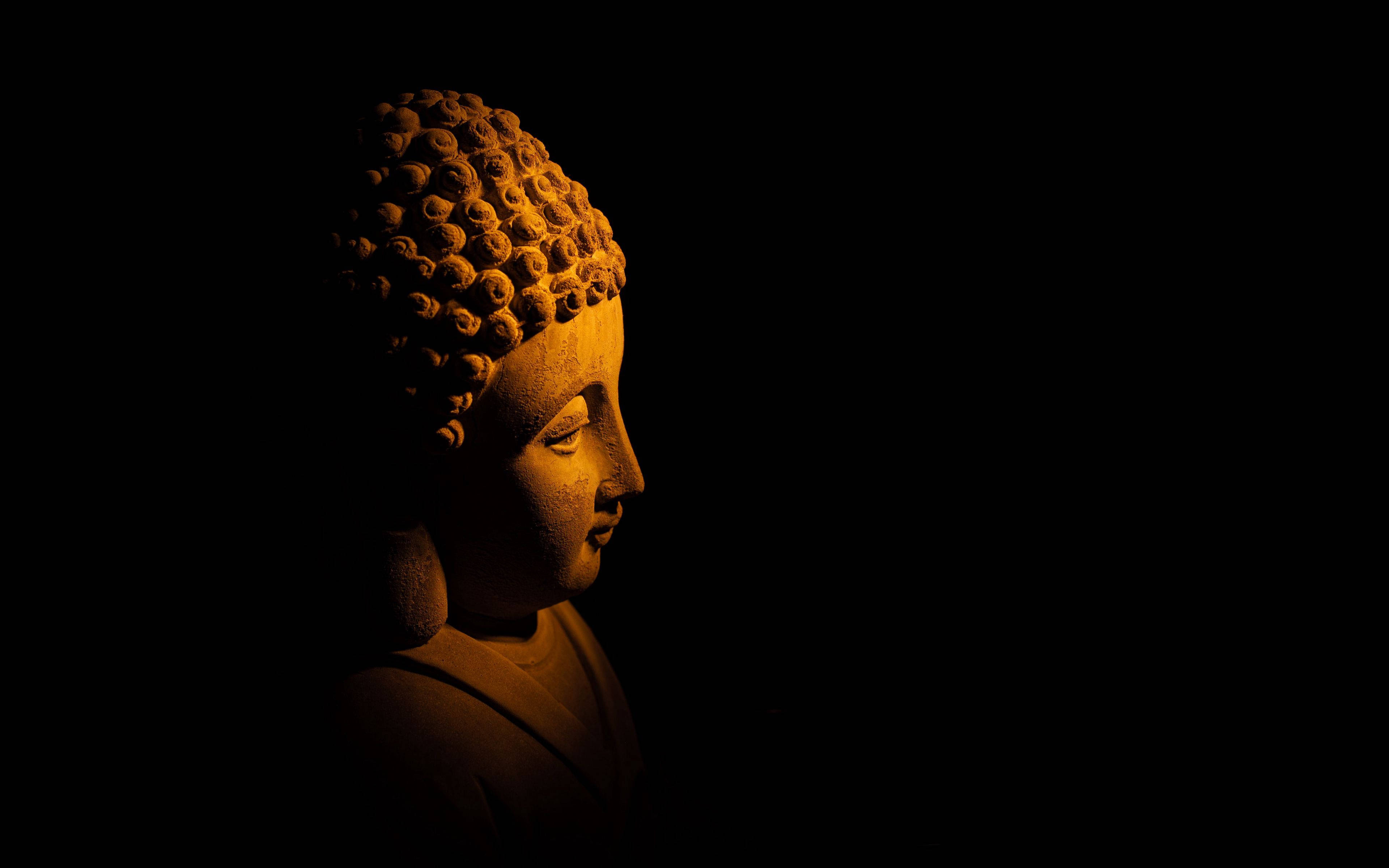 Statue Aesthetic 桌布 壁紙 — 一尊寧靜的佛陀側面雕像，沐浴在溫暖的金色光芒中，背景是深邃的黑色。