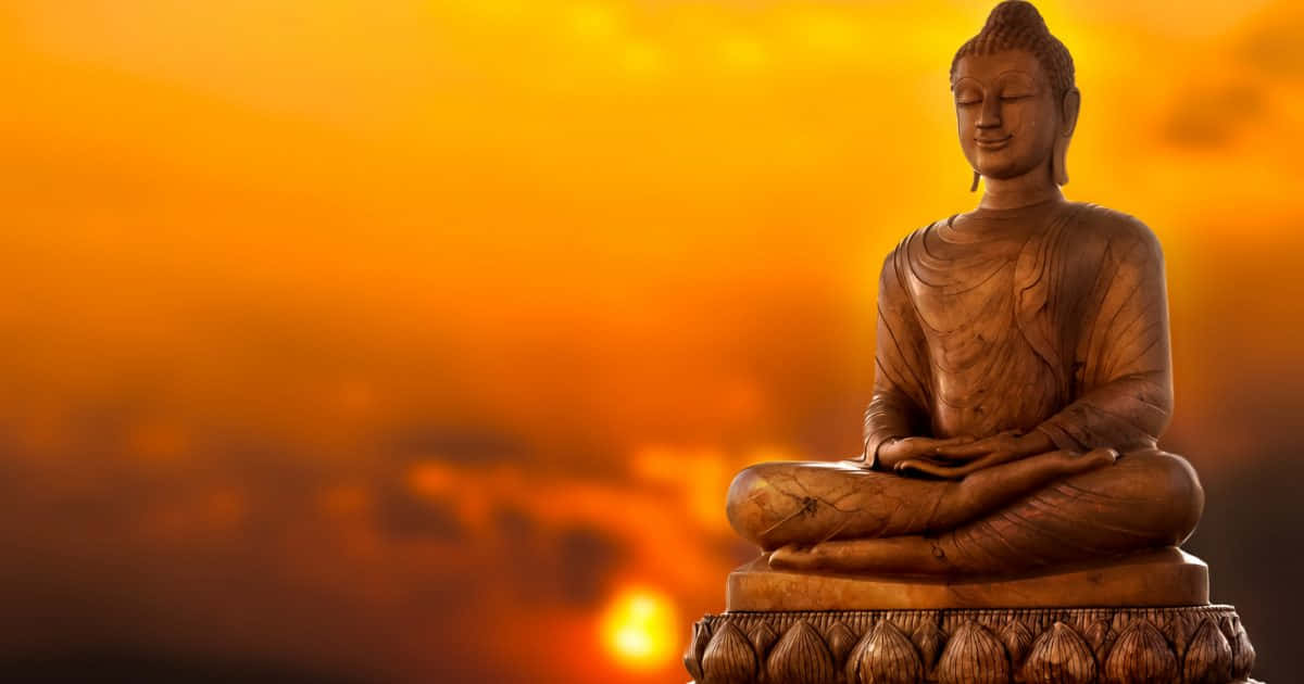 Peaceful 桌布 壁紙 — 一尊寧靜的木製佛像盤腿坐在基座上，背景是發光的橙色日落天空。
