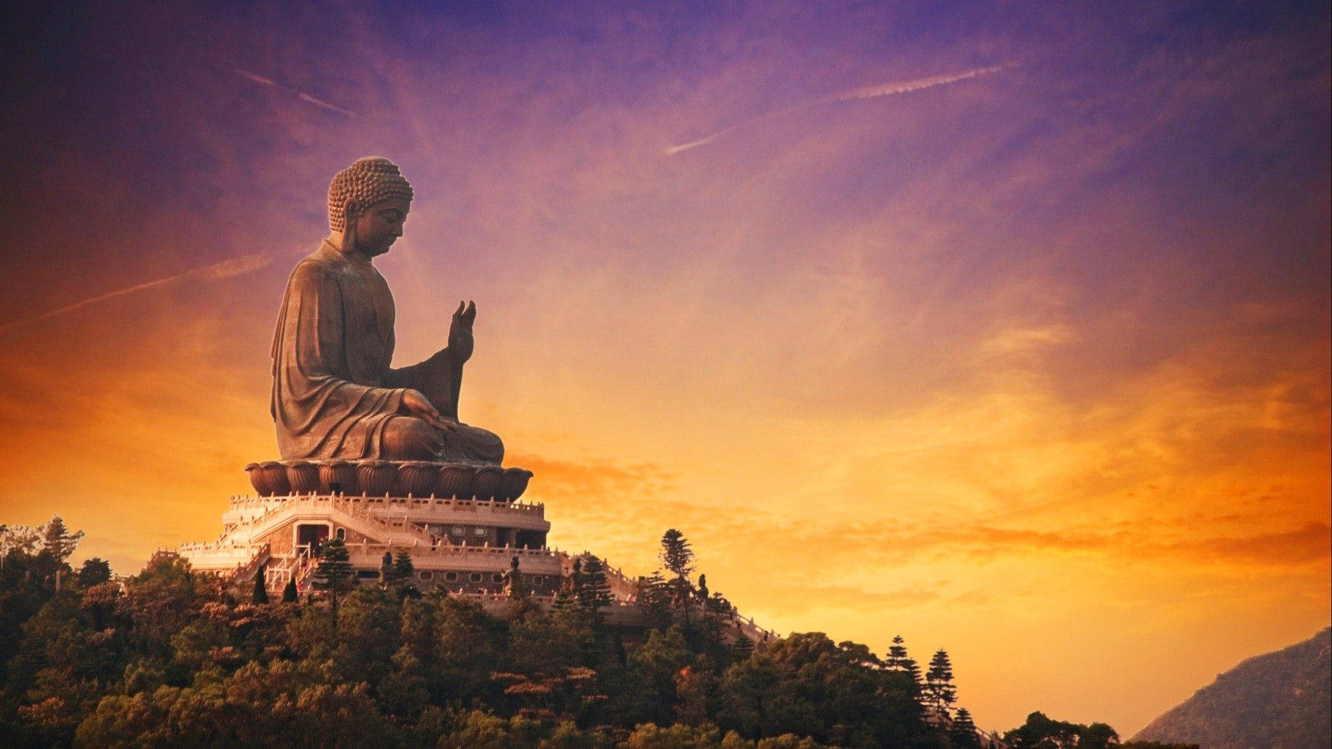 god laptop 桌布 壁紙 — 一尊巨大的佛像安詳地坐在山頂上，金色的夕陽光芒將天空染上溫暖的色調。