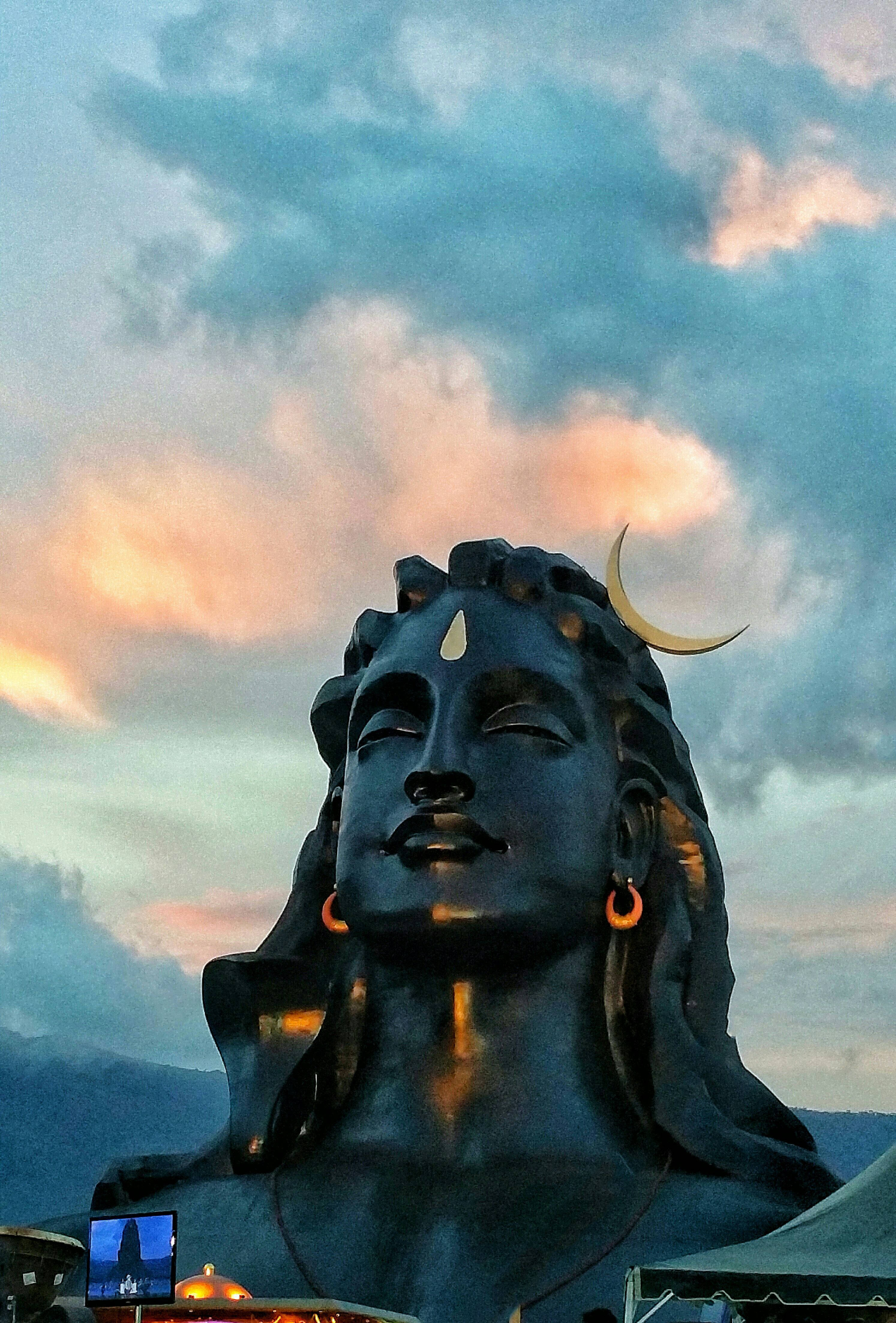 Lord Shiva 桌布 壁紙 — 一尊巨大的深色濕婆神像，飾有新月，點綴著繪有柔和粉紅和藍色雲彩的暮色天空。
