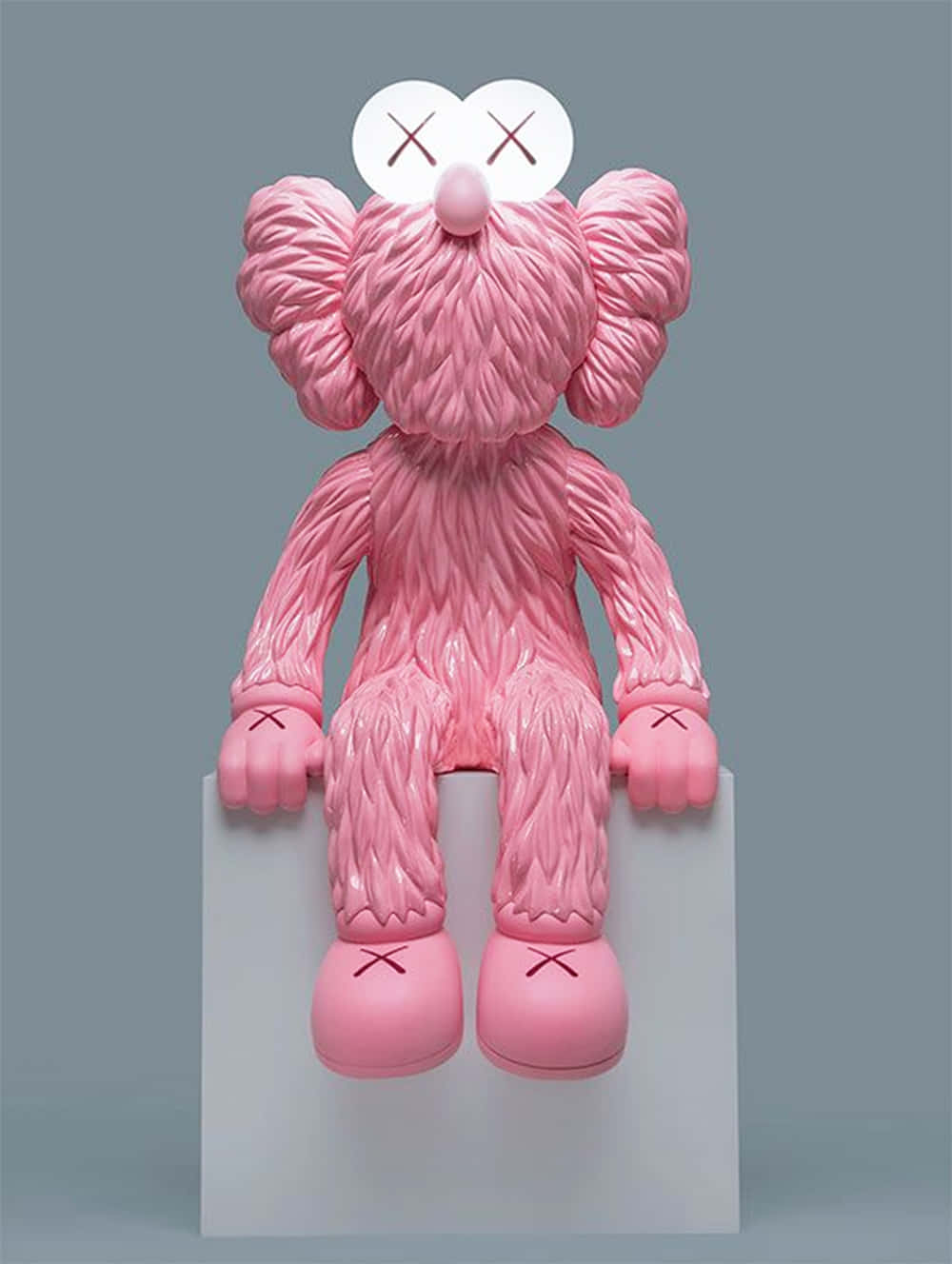 Kaws Bff Pink 桌布 壁紙 — 一尊帶有X形眼睛的光澤粉紅色KAWS雕塑，靜靜地坐在白色底座上，背景為柔和的灰色。