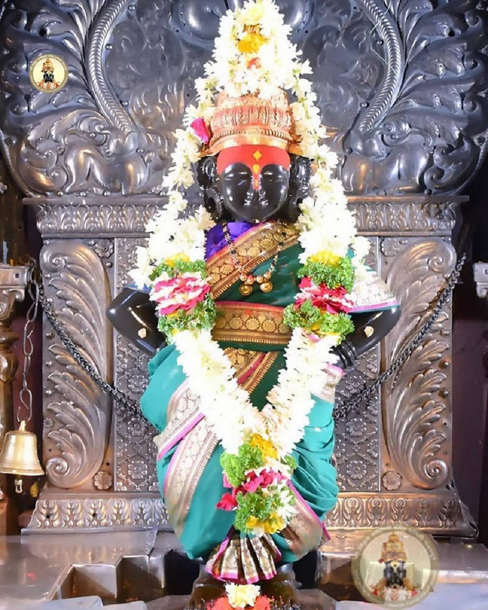 Hindu Temple 桌布 壁紙 — 一尊深色皮膚的印度教神像，飾以鮮豔花環和金飾，立於華麗的銀色神龕前。
