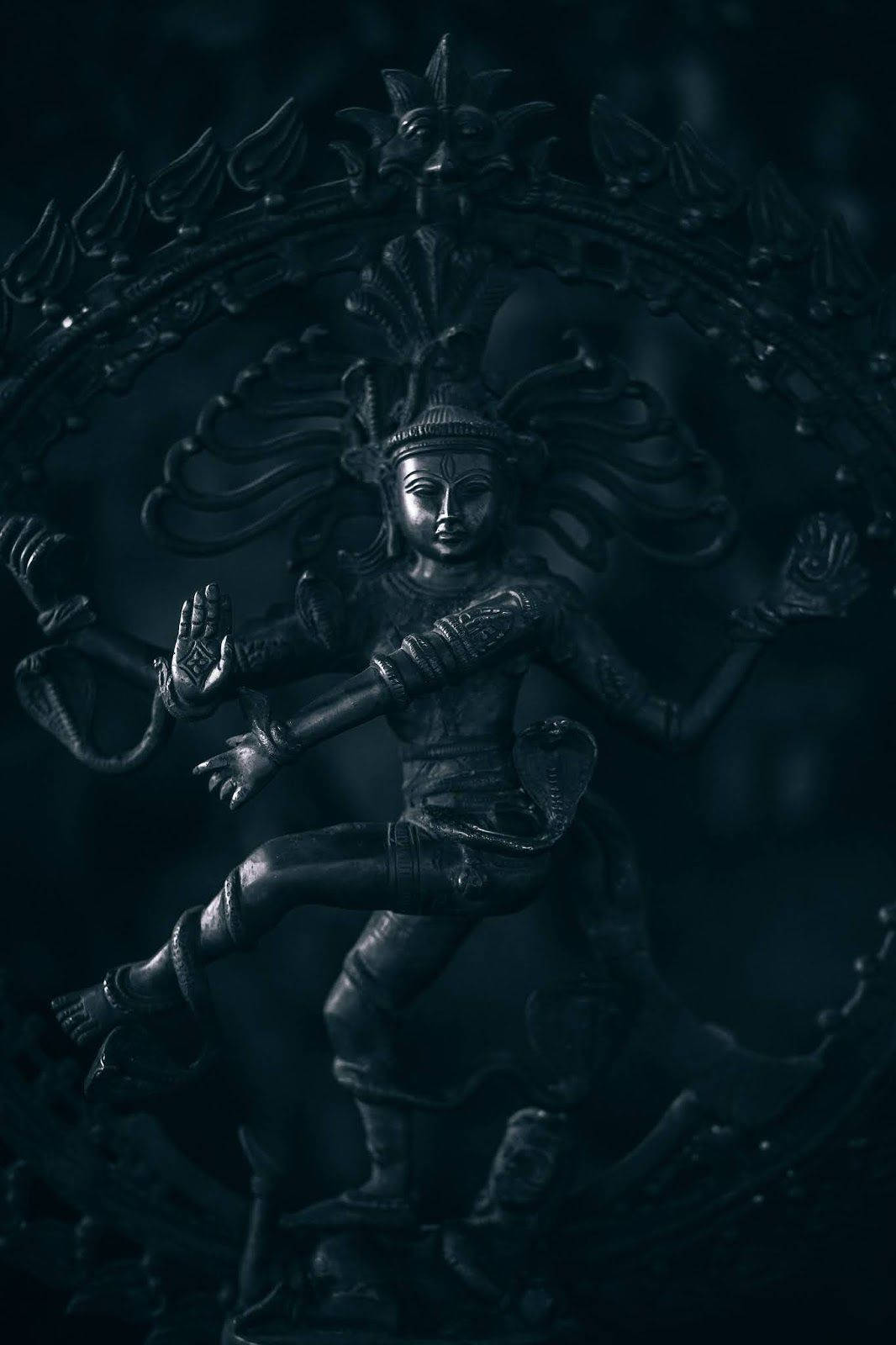 shiva dark 桌布 壁紙 — 一尊深色金屬質感的濕婆納塔拉賈雕像，在圓形光環中起舞，細節精緻，燈光效果戲劇化。