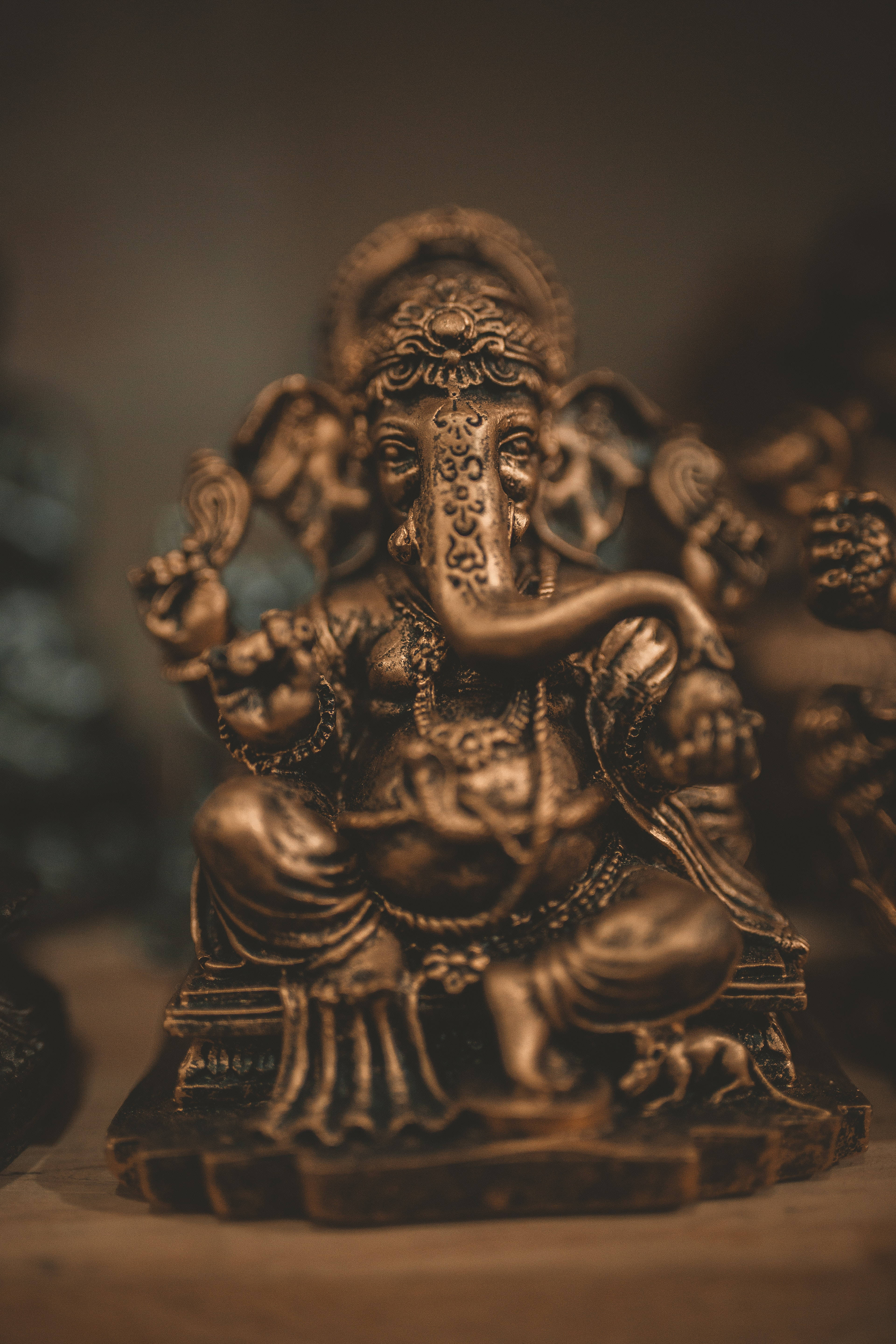 ganesh 4K 桌布 壁紙 — 一尊精細的青銅象頭神像，安詳地坐著，帶有複雜的雕刻和優雅彎曲的長鼻。