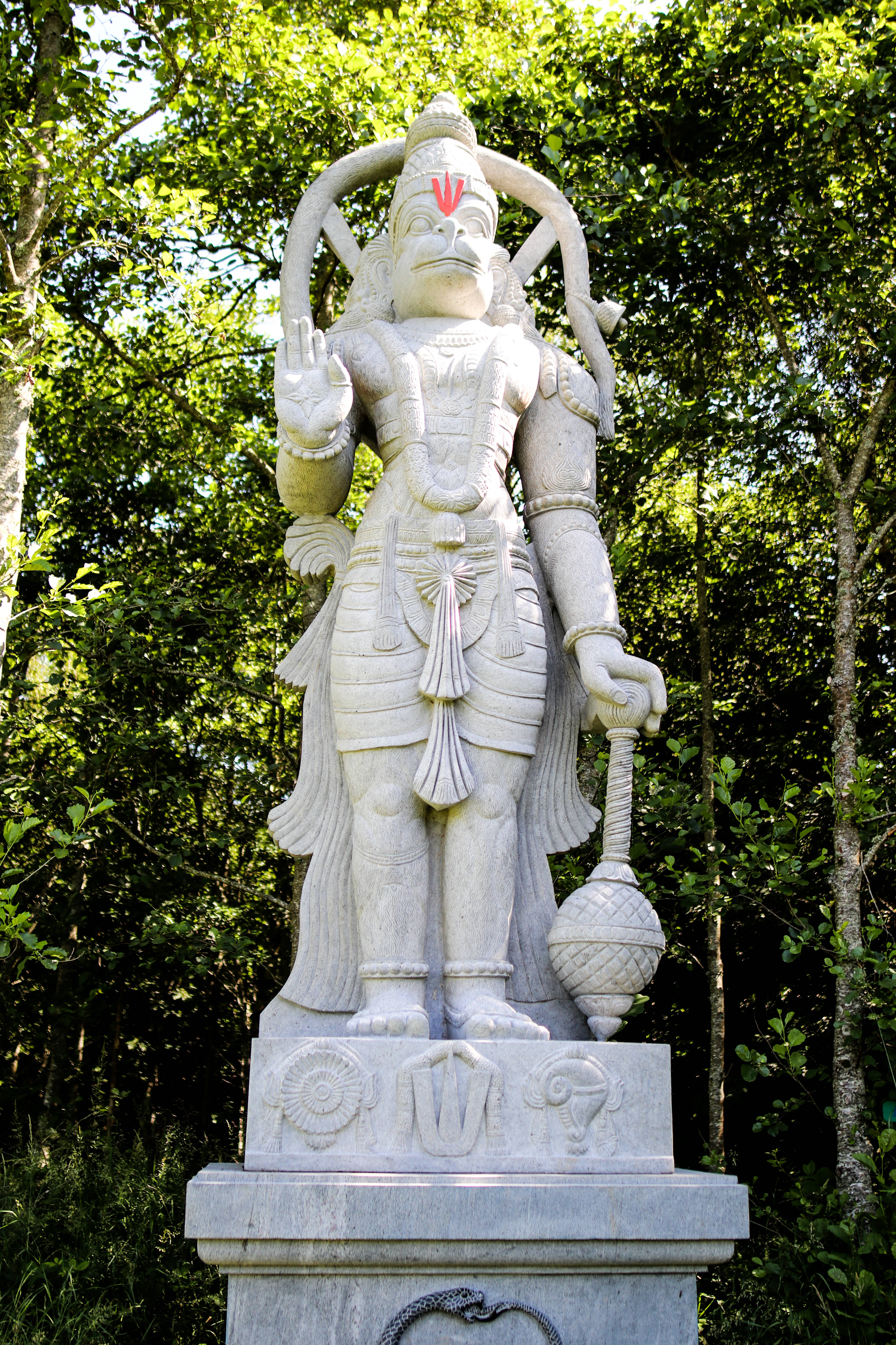 hanuman art 桌布 壁紙 — 一尊精緻的哈努曼石像矗立在陽光普照的茂密綠色森林中。